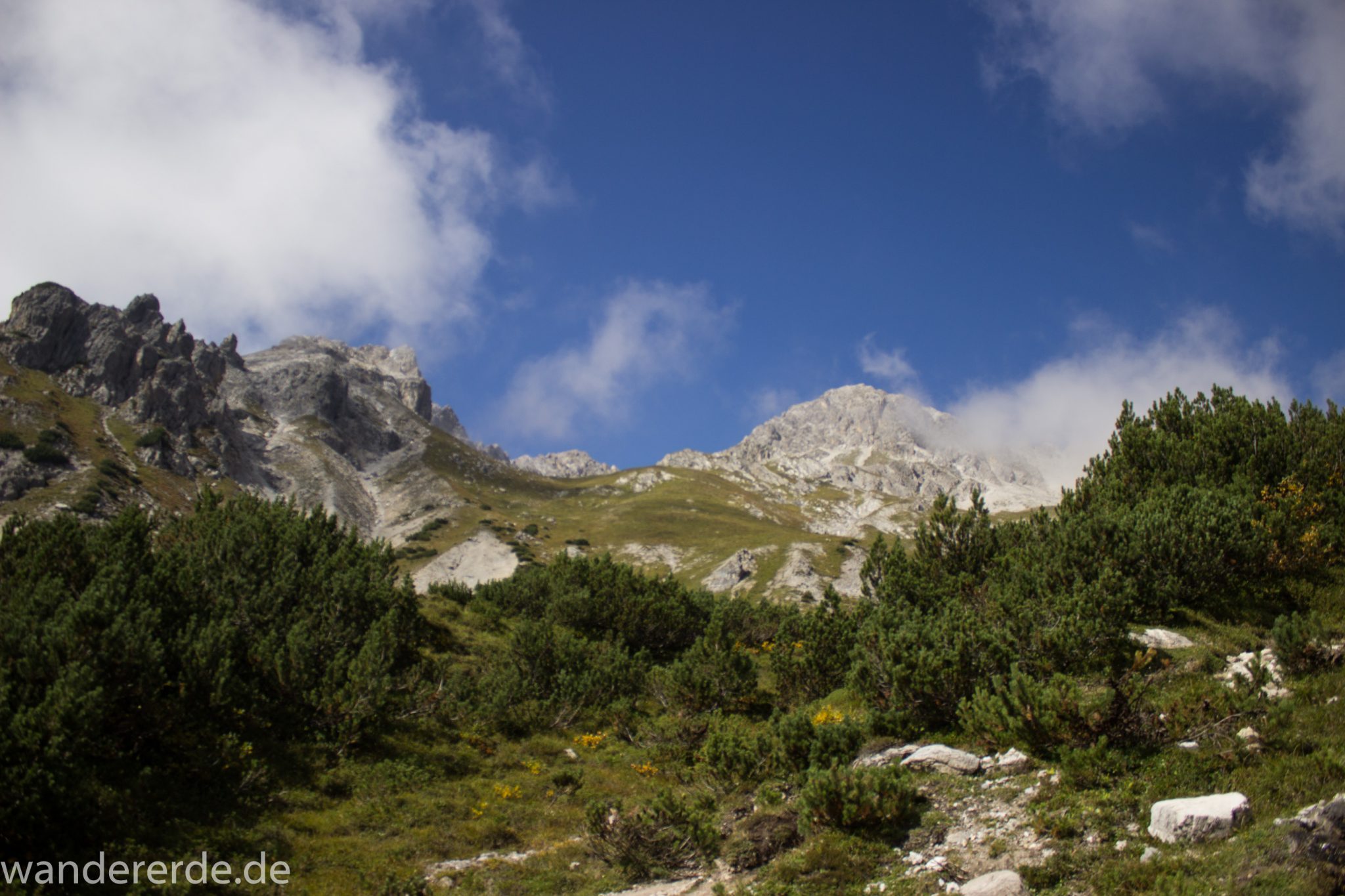 Alpenüberquerung Fernwanderweg E5 Oberstdorf Meran, 3. Etappe von Memminger Hütte zur Skihütte Zams, nach Erreichen der Seescharte folgt ein sehr langer und steiler Abstieg ins Lochbachtal auf schmalem Wanderpfad Richtung Zams, Aussicht auf Berge der Alpen und Bergwiesen, grüne Vegetation ist wieder erreicht