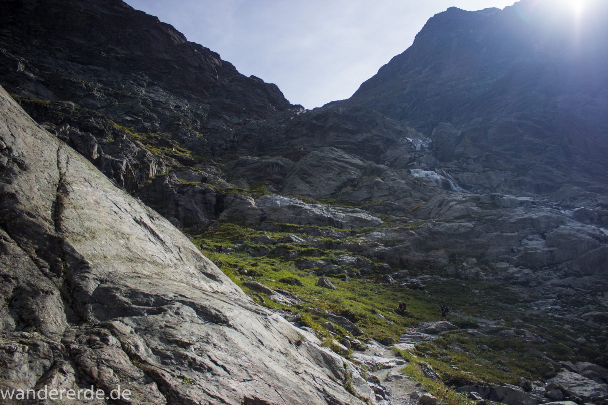 Alpenüberquerung Fernwanderweg E5 Oberstdorf Meran, 4. Etappe von Skihütte Zams zur Braunschweiger Hütte, herrliches Wanderwetter bei strahlendem Sonnenschein, Blick auf Wanderer unterwegs auf schönem und schmalem Wanderweg während Aufstieg zur Braunschweiger Hütte über Wasserfall Weg, Wanderweg über Wasserfall wird zunehmend steiler und dauert lange, Aussicht auf die schönen Berge der Alpen und noch etwas grüne Vegetation