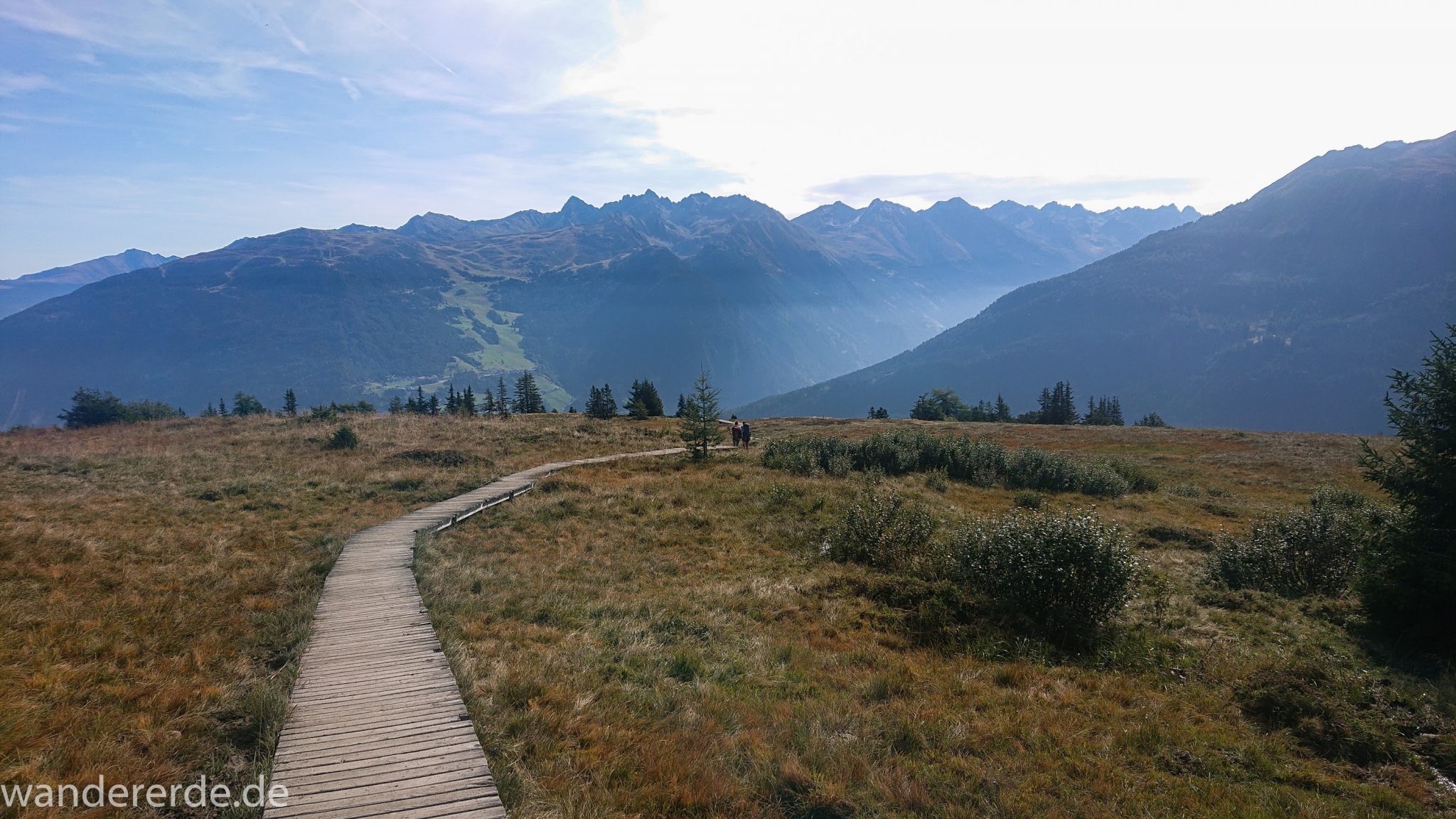 Alpenüberquerung Fernwanderweg E5 Oberstdorf Meran, 4. Etappe von Skihütte Zams zur Braunschweiger Hütte, von der Bergstation der Venet Bergbahn über den Venetrundweg nach Wenns, tolle Aussicht auf die Berge der Alpen und grüne Vegetation, herrliches Wanderwetter bei strahlendem Sonnenschein, Wanderer auf schönem, angenehmem Wanderweg Venetrundweg über Galfun Alm und Gogles Alm auf dem Weg nach Wenns, nur einige kurze steile Abschnitte