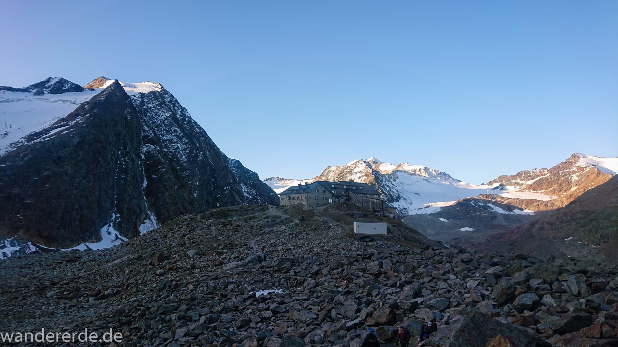 Alpenüberquerung Fernwanderweg E5 Oberstdorf Meran, 5. Etappe von Braunschweiger Hütte zur Martin-Busch-Hütte, zu Beginn der 5. Etappe Blick zurück auf die Braunschweiger Hütte und die umliegenden Berge der Alpen, danach steiler und schmaler Wanderweg mit viel Geröll hinauf zum Pitztaler Jöchl, beeindruckende Berge türmen sich vor einem auf, Reste von Schneefeldern