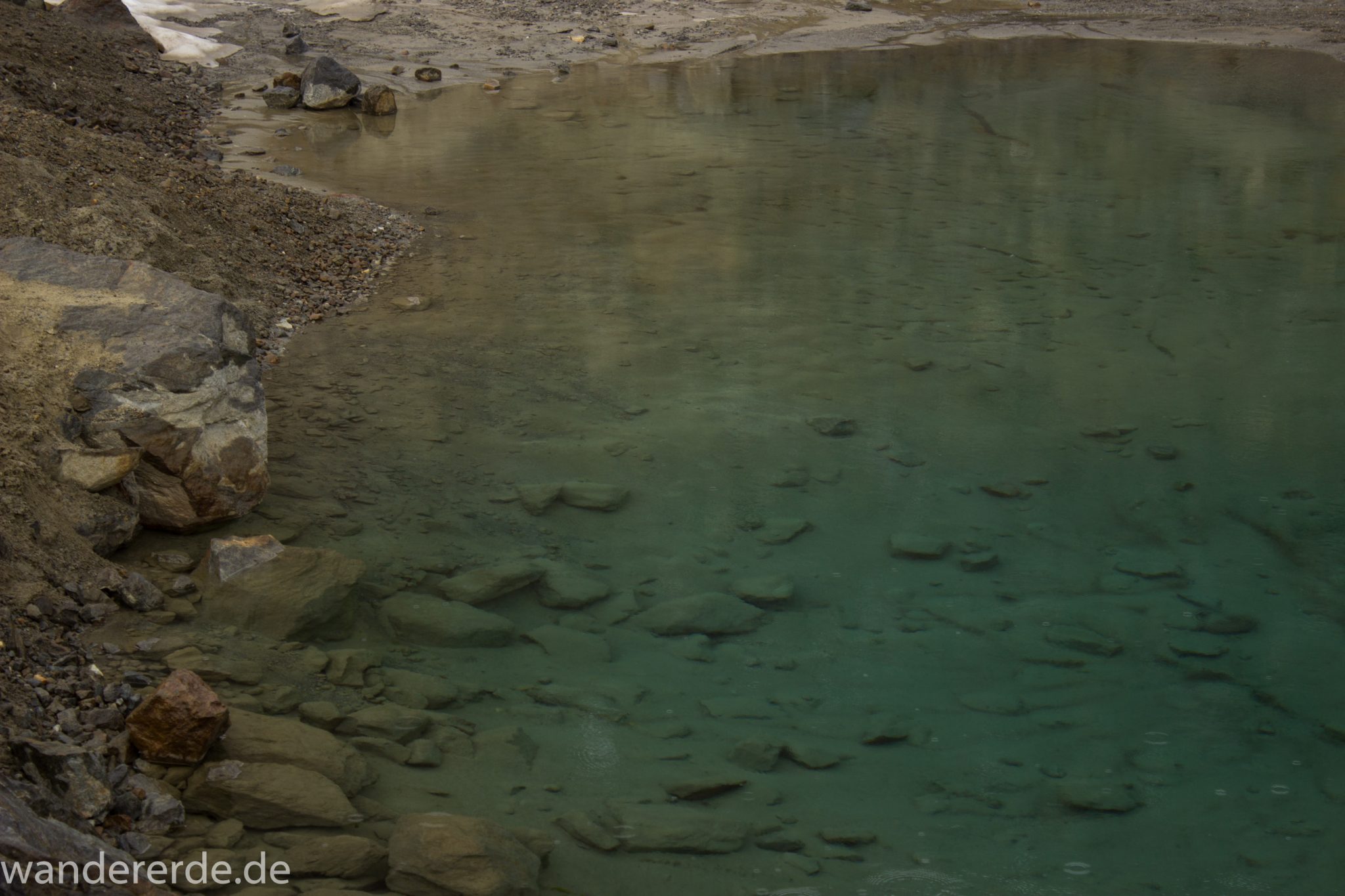 Alpenüberquerung Fernwanderweg E5 Oberstdorf Meran, 6. Etappe von Martin-Busch-Hütte nach Vernagt / Meran, die letzte Etappe der Alpenüberquerung auf dem E5 startet mit dem Aufstieg zur Similaun-Hütte, dem höchsten Punkt der gesamten Alpenüberquerung, umliegende sehr beeindruckende Bergwelt erscheint unwirklich und mystisch, Berghänge mit viel Geröll, Wanderweg verläuft zunächst gering ansteigend neben einem Bach und dann steil bergauf, Blick auf kleinen Bergsee mit kristallklarem Wasser