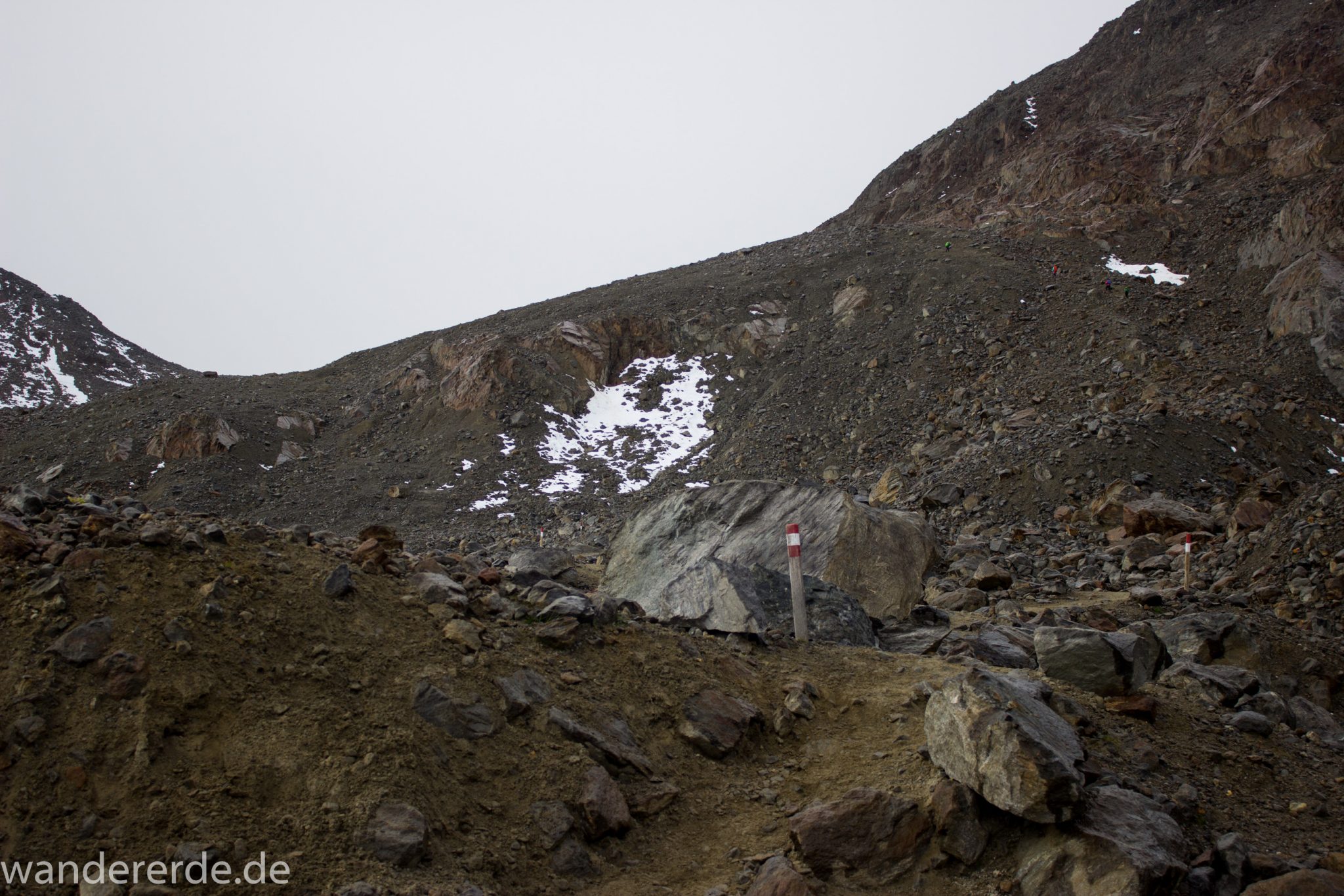 Alpenüberquerung Fernwanderweg E5 Oberstdorf Meran, 6. Etappe von Martin-Busch-Hütte nach Vernagt / Meran, die letzte Etappe der Alpenüberquerung auf dem E5 startet mit dem Aufstieg zur Similaun-Hütte, dem höchsten Punkt der gesamten Alpenüberquerung, umliegende sehr beeindruckende Bergwelt erscheint unwirklich und mystisch, Berghänge mit viel Geröll, Wanderweg verläuft zunächst gering ansteigend neben einem Bach und dann steil bergauf, Blick auf Wanderer auf schmalem, steilem Wanderweg, Wegmarkierung mit Holzpoller