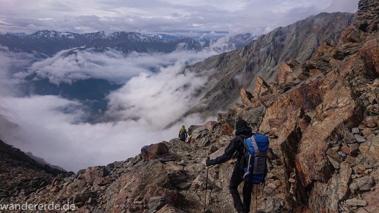 Alpenüberquerung Fernwanderweg E5 Oberstdorf Meran, 6. Etappe von Martin-Busch-Hütte nach Vernagt / Meran, die letzte Etappe der Alpenüberquerung auf dem E5 startet mit dem Aufstieg zur Similaun-Hütte, dem höchsten Punkt der gesamten Alpenüberquerung, umliegende sehr beeindruckende Bergwelt erscheint unwirklich und mystisch, Berghänge mit viel Geröll, Wanderweg verläuft nach der Similaun-Hütte steil abwärts Richtung Vernagt im Schnalstal, Wanderer während steilem Abstieg auf ausgesetztem Pfad
