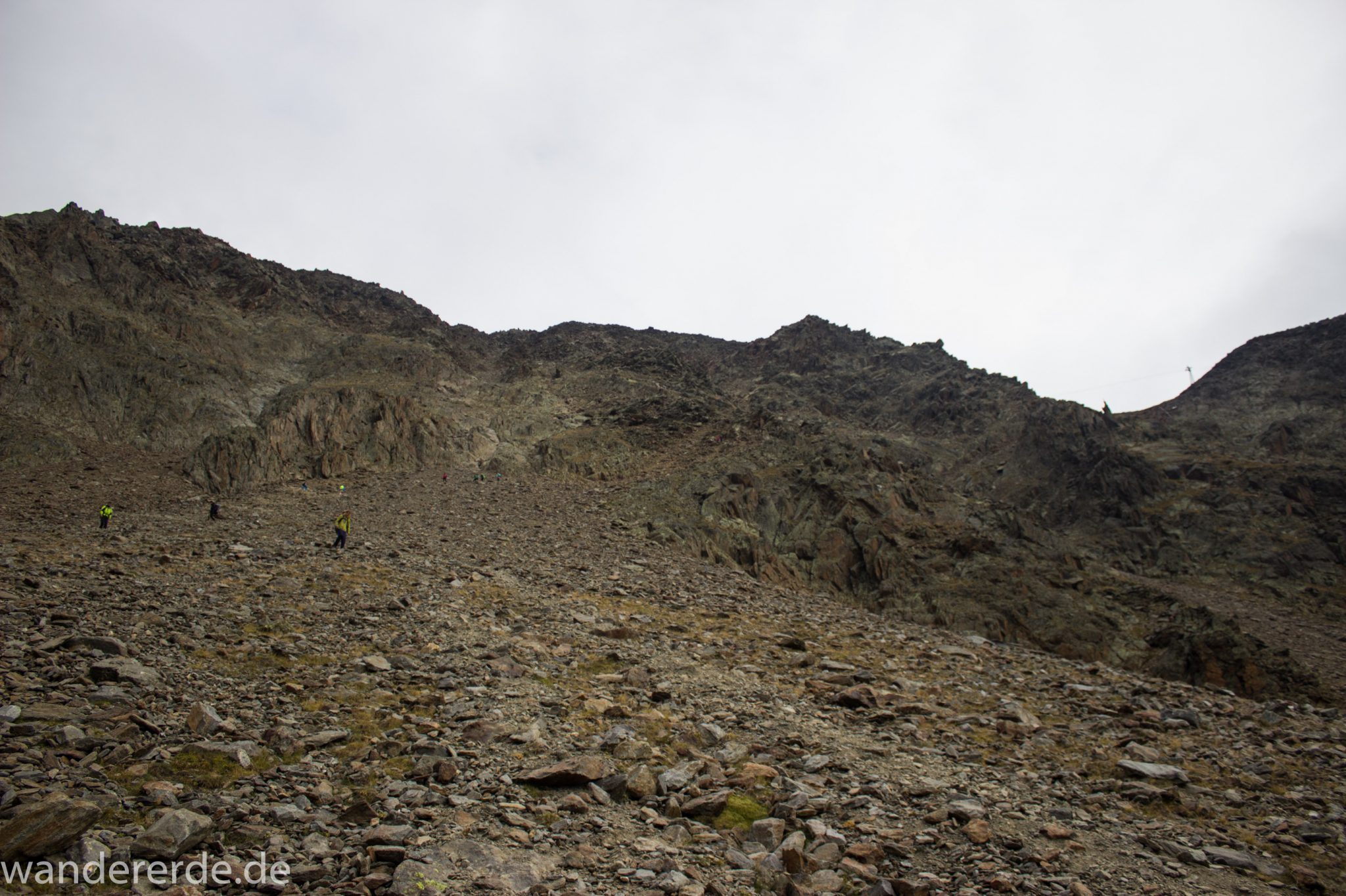 Alpenüberquerung Fernwanderweg E5 Oberstdorf Meran, 6. Etappe von Martin-Busch-Hütte nach Vernagt / Meran, die letzte Etappe der Alpenüberquerung auf dem E5 startet mit dem Aufstieg zur Similaun-Hütte, dem höchsten Punkt der gesamten Alpenüberquerung, umliegende sehr beeindruckende Bergwelt erscheint unwirklich und mystisch, Berghänge mit viel Geröll, Wanderweg verläuft nach der Similaun-Hütte steil abwärts Richtung Vernagt im Schnalstal, Wanderer während steilem Abstieg auf ausgesetztem Pfad