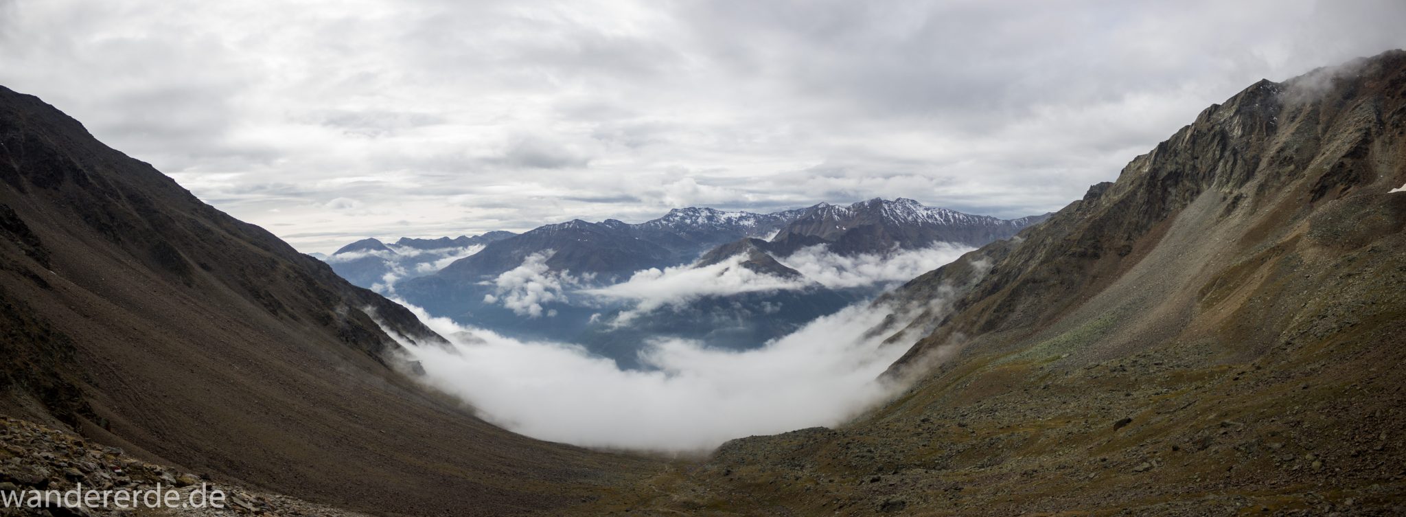 Alpenüberquerung Fernwanderweg E5 Oberstdorf Meran, 6. Etappe von Martin-Busch-Hütte nach Vernagt / Meran, nach dem Aufstieg zur Similaun-Hütte auf der letzten Etappe der Alpenüberquerung auf dem E5 verläuft der Wanderweg steil abwärts Richtung Vernagt im Schnalstal,  Blick auf Bergmassiv während Abstieg, erscheint unwirklich und mystisch, Berghänge mit viel Geröll, Wanderung mit steilem Abstieg auf ausgesetztem Pfad