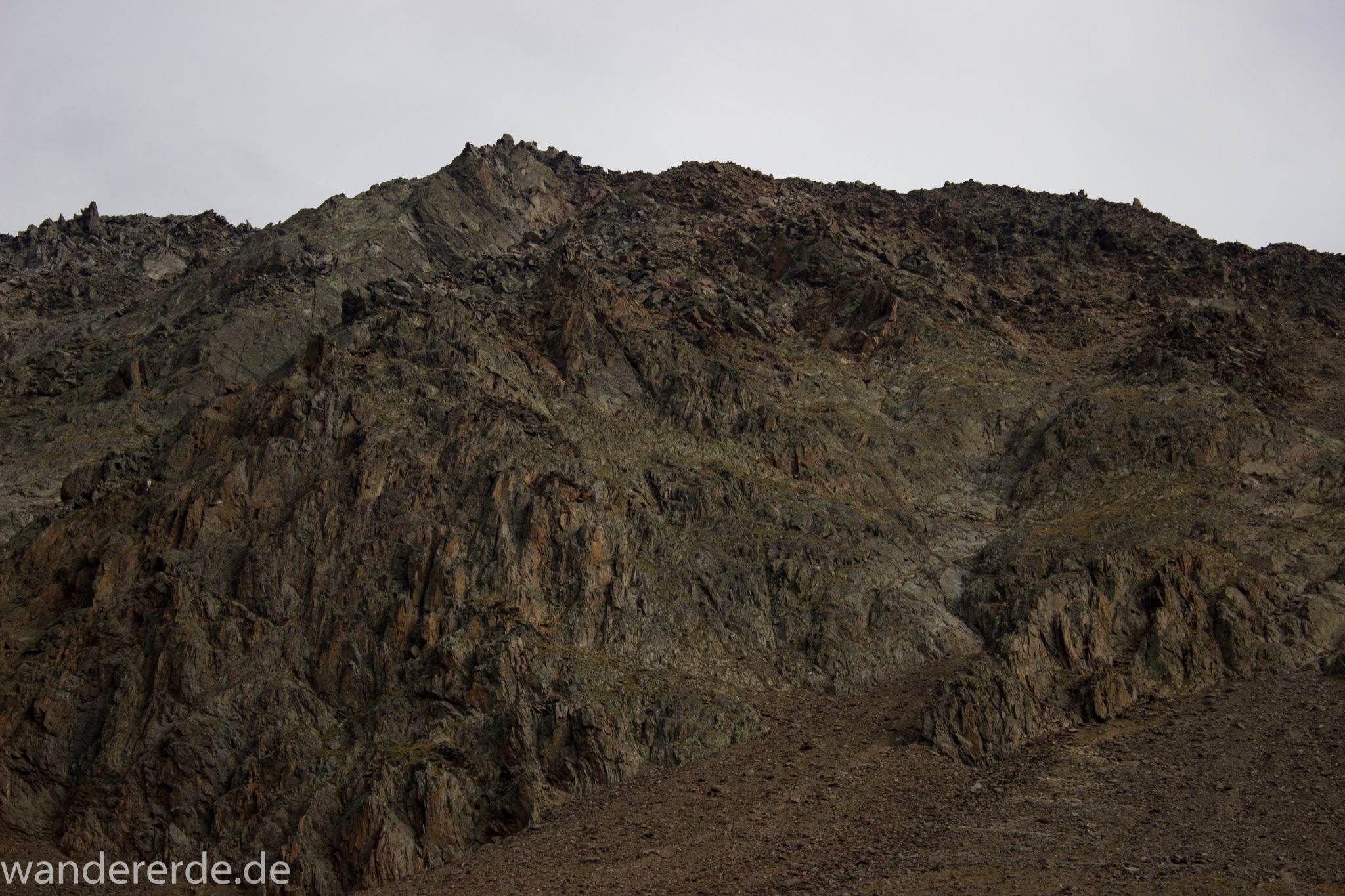 Alpenüberquerung Fernwanderweg E5 Oberstdorf Meran, 6. Etappe von Martin-Busch-Hütte nach Vernagt / Meran, nach dem Aufstieg zur Similaun-Hütte auf der letzten Etappe der Alpenüberquerung auf dem E5 verläuft der Wanderweg steil abwärts Richtung Vernagt im Schnalstal,  Blick auf Berge während Abstieg, erscheint unwirklich und mystisch, Berghänge mit viel Geröll, Wanderung mit steilem Abstieg auf ausgesetztem Pfad