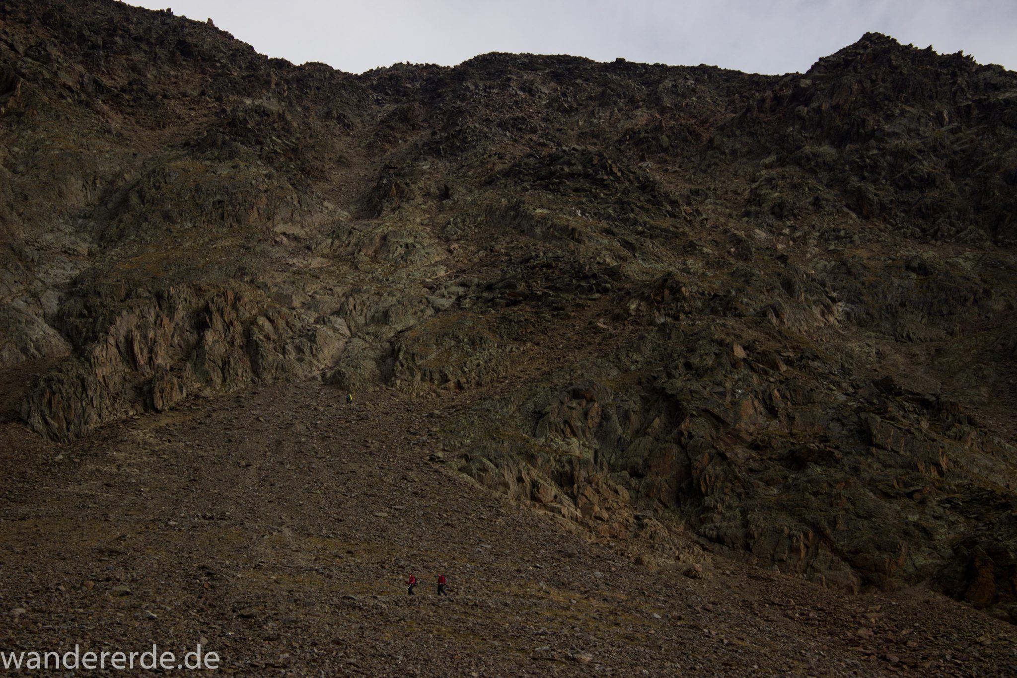 Alpenüberquerung Fernwanderweg E5 Oberstdorf Meran, 6. Etappe von Martin-Busch-Hütte nach Vernagt / Meran, nach dem Aufstieg zur Similaun-Hütte auf der letzten Etappe der Alpenüberquerung auf dem E5 verläuft der Wanderweg steil abwärts Richtung Vernagt im Schnalstal,  Blick auf Berge während Abstieg, erscheint unwirklich und mystisch, Berghänge mit viel Geröll, Wanderung mit steilem Abstieg auf ausgesetztem Pfad, Blick auf Wanderer während Abstieg ins Schnalstal