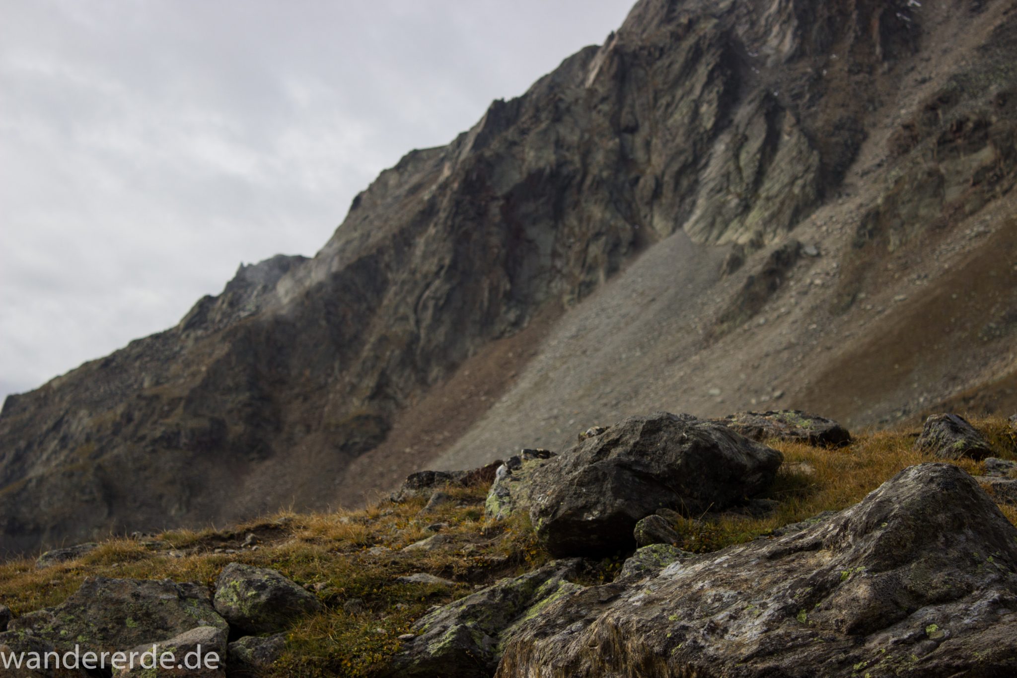 Alpenüberquerung Fernwanderweg E5 Oberstdorf Meran, 6. Etappe von Martin-Busch-Hütte nach Vernagt / Meran, nach dem Aufstieg zur Similaun-Hütte auf der letzten Etappe der Alpenüberquerung auf dem E5 verläuft der Wanderweg steil abwärts Richtung Vernagt im Schnalstal,  Blick auf Berge während Abstieg, erscheint unwirklich und mystisch, Berghänge mit viel Geröll, Wanderung mit steilem Abstieg auf ausgesetztem Pfad