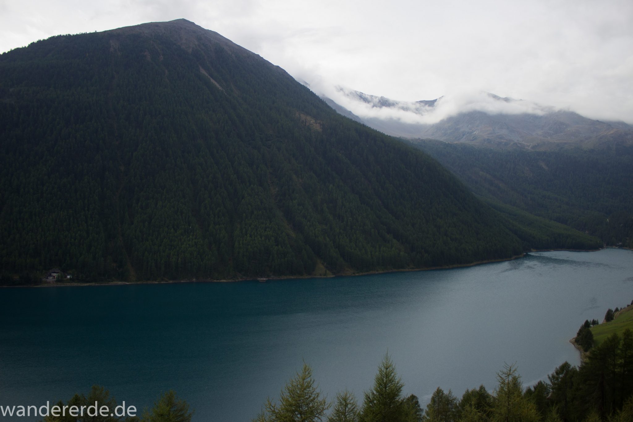 Alpenüberquerung Fernwanderweg E5 Oberstdorf Meran, 6. Etappe von Martin-Busch-Hütte nach Vernagt / Meran, nach dem Aufstieg zur Similaun-Hütte auf der letzten Etappe der Alpenüberquerung auf dem E5 verläuft der Wanderweg steil abwärts Richtung Vernagt im Schnalstal,  Blick auf den Stausee in Vernagt und die umliegenden Wälder, saftig grüne Vegetation, Stausee ist das Ziel der Alpenüberquerung auf dem E5, nach Meran geht es weiter mit dem Bus und Zug