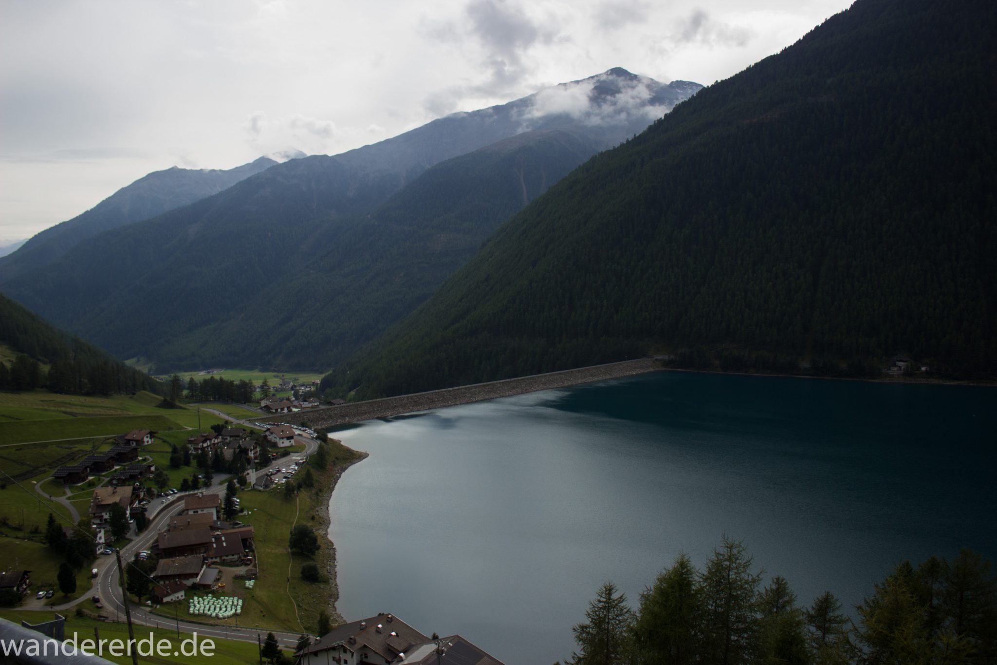 Alpenüberquerung Fernwanderweg E5 Oberstdorf Meran, 6. Etappe von Martin-Busch-Hütte nach Vernagt / Meran, nach dem Aufstieg zur Similaun-Hütte auf der letzten Etappe der Alpenüberquerung auf dem E5 verläuft der Wanderweg steil abwärts Richtung Vernagt im Schnalstal,  Blick auf den Stausee in Vernagt und die umliegenden Wälder, saftig grüne Vegetation, Stausee ist das Ziel der Alpenüberquerung auf dem E5, nach Meran geht es weiter mit dem Bus und Zug