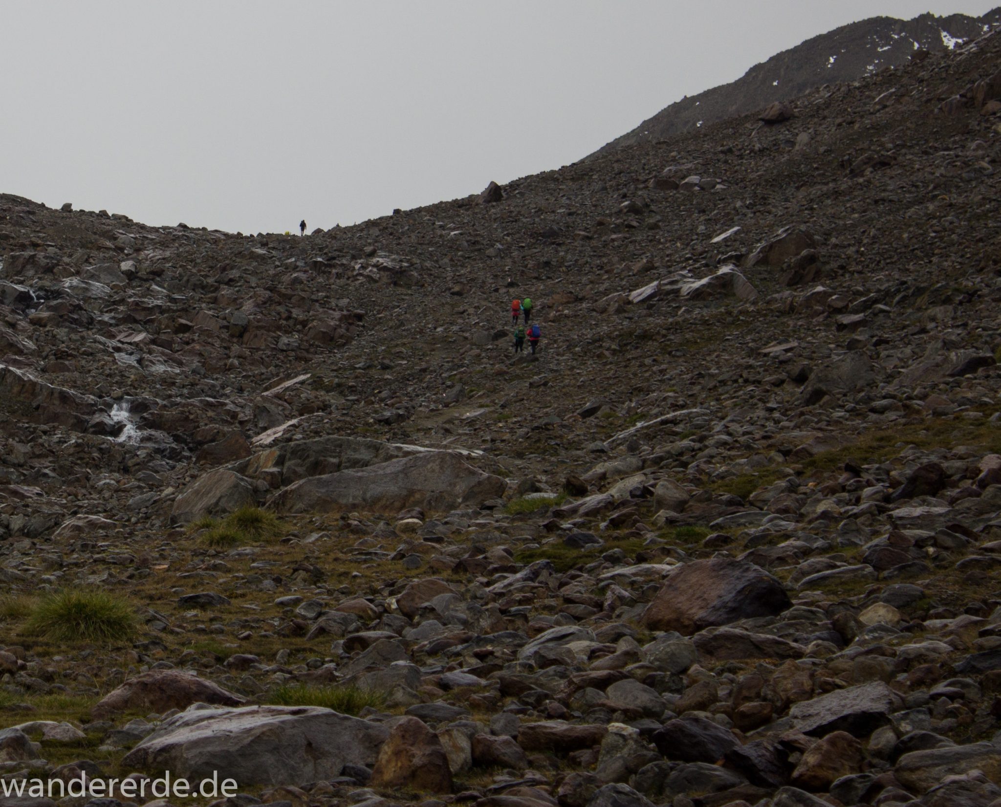 Alpenüberquerung Fernwanderweg E5 Oberstdorf Meran, 6. Etappe von Martin-Busch-Hütte nach Vernagt / Meran, die letzte Etappe der Alpenüberquerung auf dem E5 startet mit dem Aufstieg zur Similaun-Hütte, dem höchsten Punkt der gesamten Alpenüberquerung, umliegende sehr beeindruckende Bergwelt erscheint unwirklich und mystisch, Berghänge mit viel Geröll, Wanderweg verläuft zunächst gering ansteigend neben einem Bach und dann steil bergauf, Blick auf Wanderer auf steilem Abschnitt