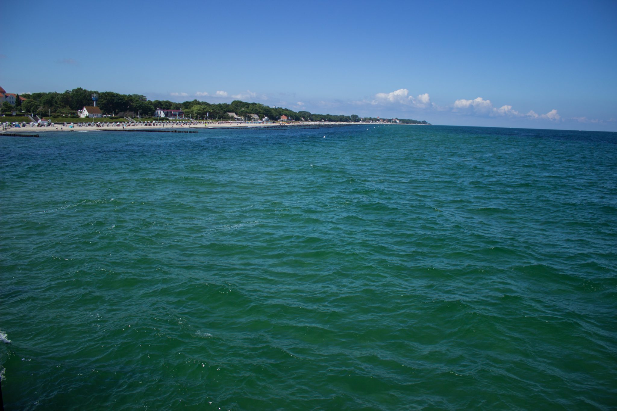 Wandern an der Ostsee von Kühlungsborn nach Börgerende auf dem E9, dritte Etappe des Wanderwegs an der Ostseeküste von Wismar nach Zingst, Blick von der Seebrücke in Kühlungsborn Richtung Ort und Strand, weite Ostsee, strahlend blauer Himmel im Sommer