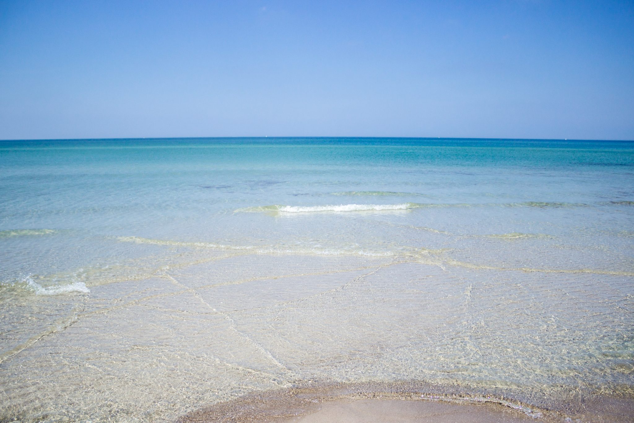 Wandern an der Ostsee von Ahrenshoop nach Zingst auf dem E9, siebte Etappe des Wanderwegs an der Ostseeküste von Wismar nach Zingst, langer, weißer Sandstrand in Ahrenshoop an der Ostsee, schönes, sauberes Meer mit klarem Wasser, kleine Wellen brechen sanft am Ufer, wolkenloser Himmel, Bild könnte auch in der Karibik entstanden sein