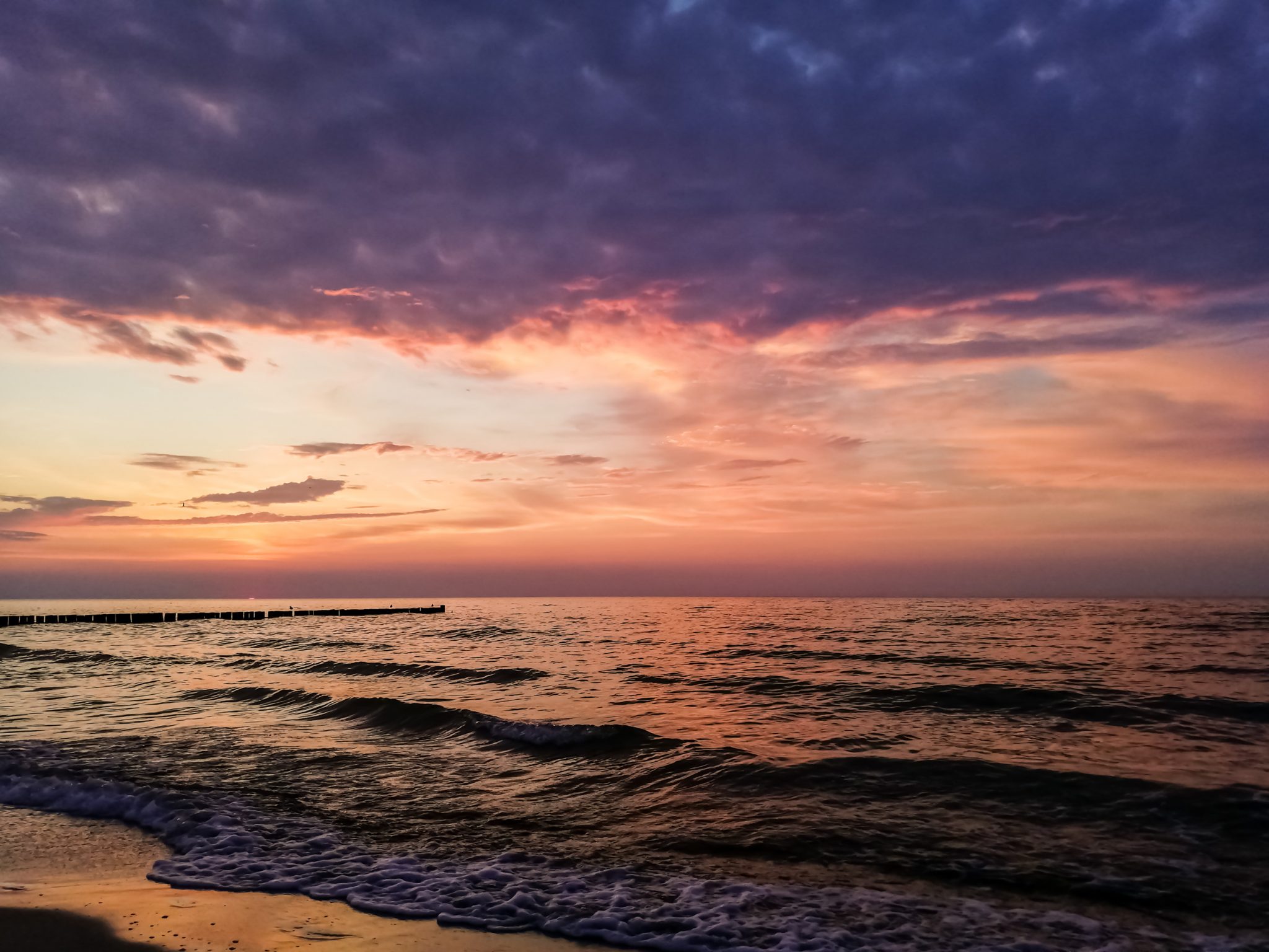 Wandern an der Ostsee von Ahrenshoop nach Zingst auf dem E9, siebte Etappe des Wanderwegs an der Ostseeküste von Wismar nach Zingst, Ziel der Wanderung an der Ostsee auf dem E9 erreicht, Ort Zingst auf der Halbinsel Fischland-Darß-Zingst, nach Gewitter traumhaftes Licht und Farben während des Sonnenuntergangs, Wellen brechen sanft am Ufer