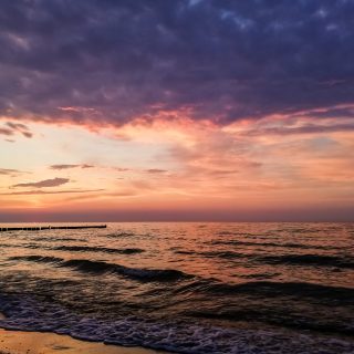Wandern an der Ostsee von Ahrenshoop nach Zingst auf dem E9, siebte Etappe des Wanderwegs an der Ostseeküste von Wismar nach Zingst, Ziel der Wanderung an der Ostsee auf dem E9 erreicht, Ort Zingst auf der Halbinsel Fischland-Darß-Zingst, nach Gewitter traumhaftes Licht und Farben während des Sonnenuntergangs, Wellen brechen sanft am Ufer