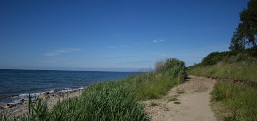 Wandern an der Ostsee vom Salzhaff nach Kühlungsborn auf dem E9 Fernwanderweg, zweite Etappe des Wanderwegs an der Ostseeküste von Wismar nach Zingst, Blick auf die schöne Ostsee im Sommer, fast menschenleerer Strand, sandiger Wanderweg mit direktem Meerblick