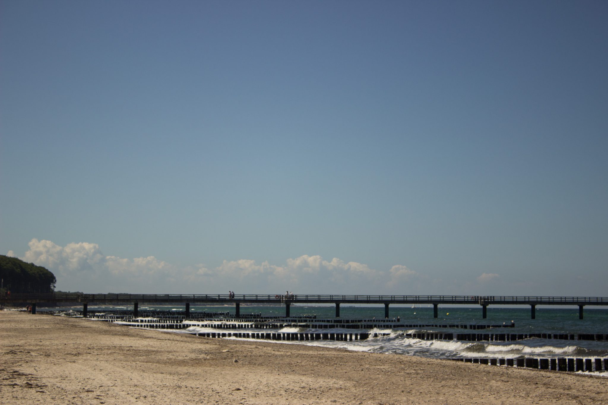Wandern an der Ostsee von Kühlungsborn nach Börgerende auf dem E9, dritte Etappe des Wanderwegs an der Ostseeküste von Wismar nach Zingst, nach Ort Kühlungsborn führt die Wanderung weiter Richtung Heiligendamm, Blick auf die Seebrücke in Heiligendamm und breiten Sandstrand an der Ostsee, Wellen brechen am Ufer