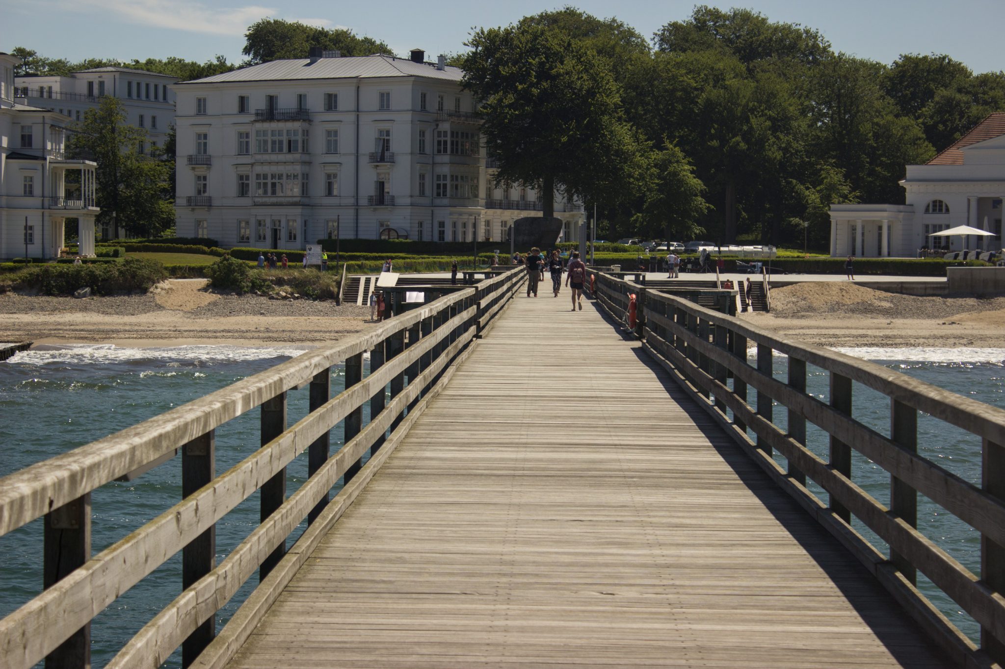 Wandern an der Ostsee von Kühlungsborn nach Börgerende auf dem E9, dritte Etappe des Wanderwegs an der Ostseeküste von Wismar nach Zingst, nach Ort Kühlungsborn führt die Wanderung weiter Richtung Heiligendamm, Blick von der Seebrücke in Heiligendamm in Richtung Ort, Spaziergänger auf der Seebrücke, Blick auf Villen in Heiligendamm