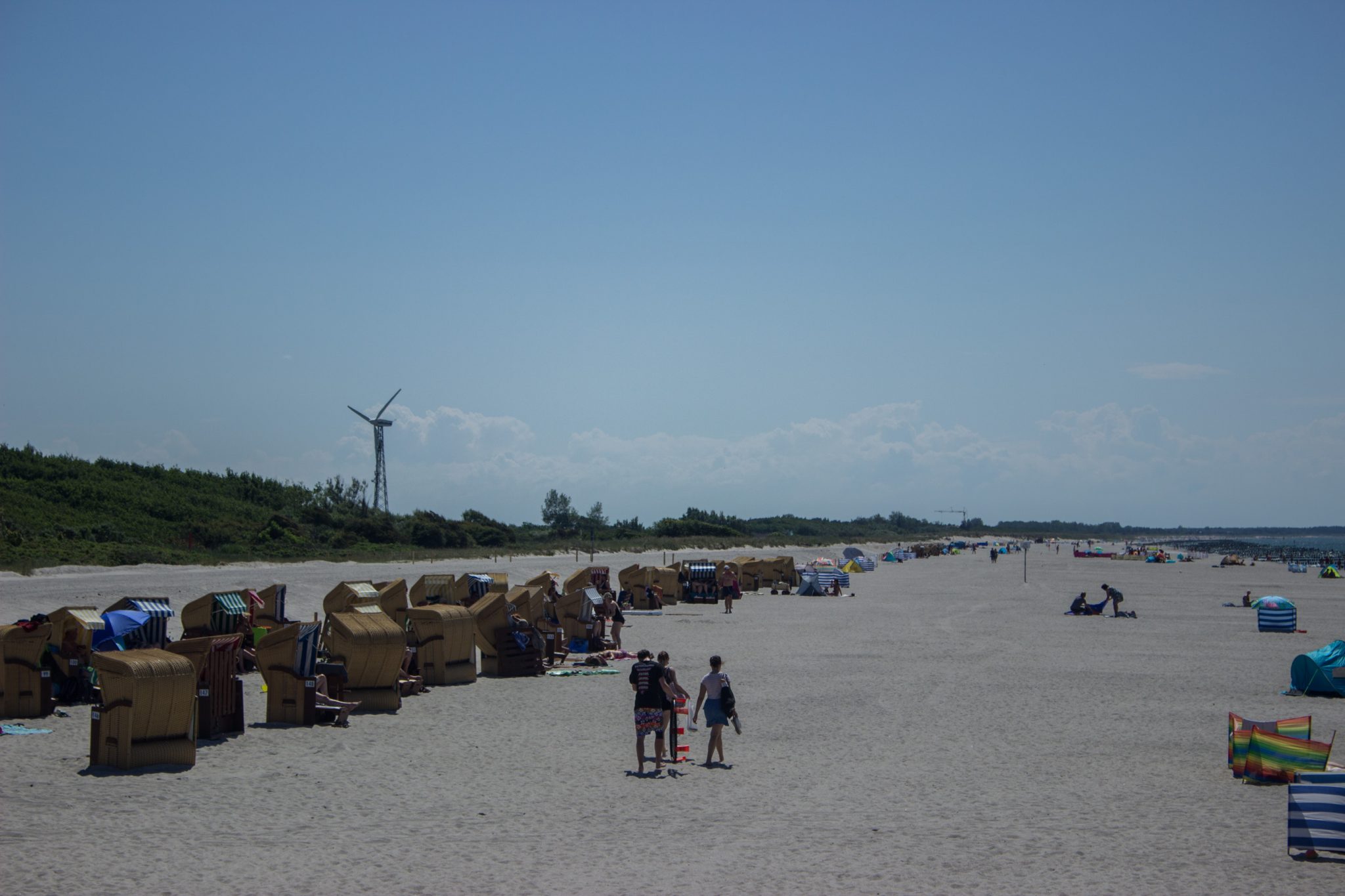 Wandern an der Ostsee von Dierhagen nach Ahrenshoop auf dem E9, sechste Etappe des Wanderwegs an der Ostseeküste von Wismar nach Zingst, am Strand an der Ostsee wandern wir bis zum Ostseebad Wustrow, traumhaft schöne Aussicht auf den breiten Sandstrand, Spaziergänger und Urlauber am Strand, wolkenloser Himmel und Sonnenschein im Sommer