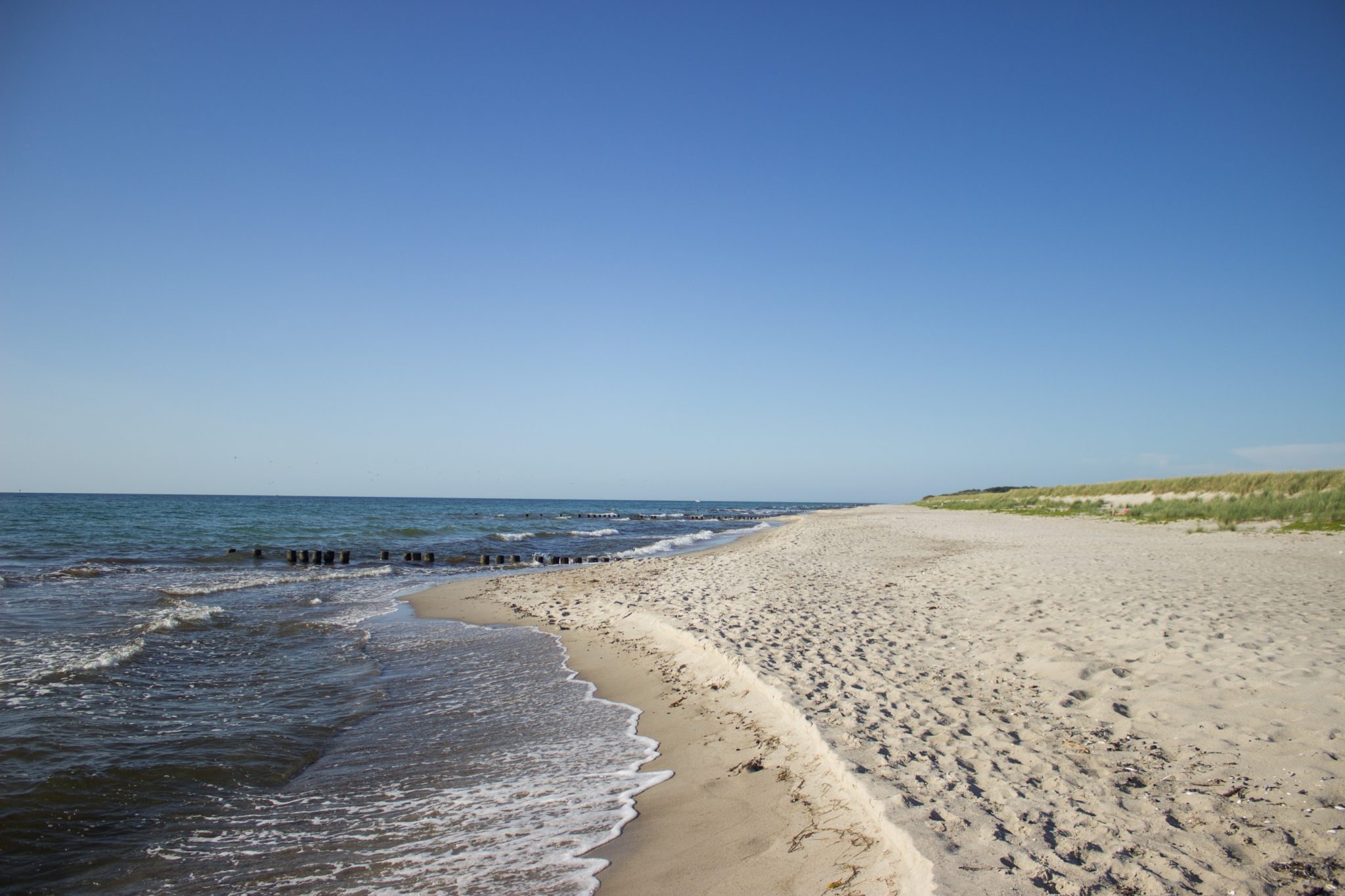 Wandern an der Ostsee von Markgrafenheide nach Dierhagen auf dem E9, fünfte Etappe des Wanderwegs an der Ostseeküste von Wismar nach Zingst, menschenleerer schöner und sehr weitläufiger Sandstrand an der Ostsee in der Nähe von Markgrafenheide, sanfte Wellen rollen ans Ufer
