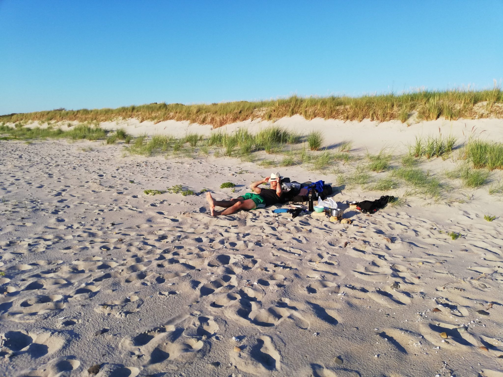 Wandern an der Ostsee von Markgrafenheide nach Dierhagen auf dem E9, fünfte Etappe des Wanderwegs an der Ostseeküste von Wismar nach Zingst, menschenleerer schöner und sehr weitläufiger Sandstrand an der Ostsee in der Nähe von Markgrafenheide, bewachsene Dünen im Hintergrund, Küstenvegetation