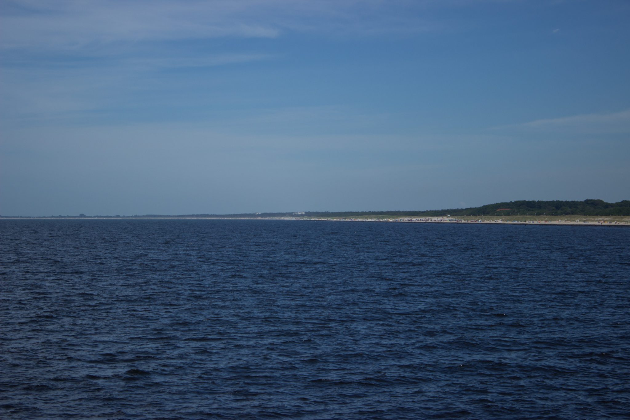 Wandern an der Ostsee von Markgrafenheide nach Dierhagen auf dem E9, fünfte Etappe des Wanderwegs an der Ostseeküste von Wismar nach Zingst, im schönen Ostseebad Graal-Müritz kann man optional auf die Seebrücke wandern, kühle, angenehme Temperatur an der Küste, Blick Richtung Land auf die breiten Strände an der Ostsee und Küstenwald, schöner Meerblick, fast wolkenloser Himmel
