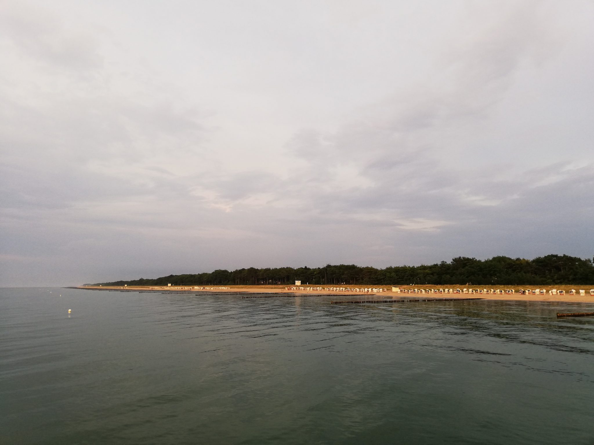 Wandern an der Ostsee von Ahrenshoop nach Zingst auf dem E9, siebte Etappe des Wanderwegs an der Ostseeküste von Wismar nach Zingst, Ziel der Wanderung an der Ostsee auf dem E9 erreicht, Ort Zingst auf der Halbinsel Fischland-Darß-Zingst, nach Gewitter traumhaftes Licht und Farben während des Sonnenuntergangs, Blick von der Seebrücke Richtung Strand, Ostsee ist ganz still, wunderschöne Lichtstimmung