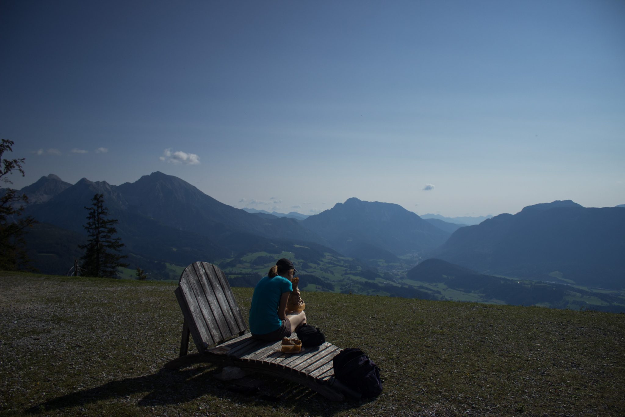 Wandern bei Windischgarsten auf den Kleinerberg über Salzabachtal, Leitersteig, Speikkogel und Schafsteig im Nationalpark Kalkalpen in Oberösterreich, Aussicht vom Kleinerberg auf das weite Tal, die umliegenden Berge und Wälder an warmem Sommertag, Wanderer genießt Aussicht, ausgiebige Pause auf Holzliege bietet sich an