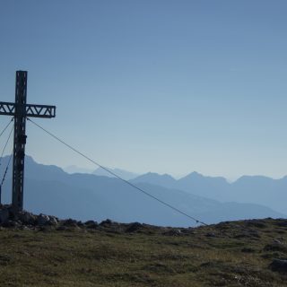 Wanderung Hoher Nock ab Windischgarsten im Nationalpark Kalkalpen in Oberösterreich, auf dem Berggipfel des Hohen Nocks mit Gipfelkreuz angekommen, großes Plateau auf dem Gipfel, tolle weite Aussichten auf die umliegenden Berge der Kalkalpen in Österreich, Wanderer genießt die Aussicht in alle Richtungen