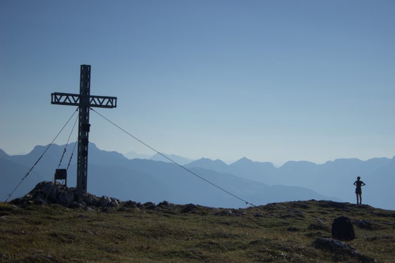 Wanderung Hoher Nock ab Windischgarsten im Nationalpark Kalkalpen in Oberösterreich, auf dem Berggipfel des Hohen Nocks mit Gipfelkreuz angekommen, großes Plateau auf dem Gipfel, tolle weite Aussichten auf die umliegenden Berge der Kalkalpen in Österreich, Wanderer genießt die Aussicht in alle Richtungen