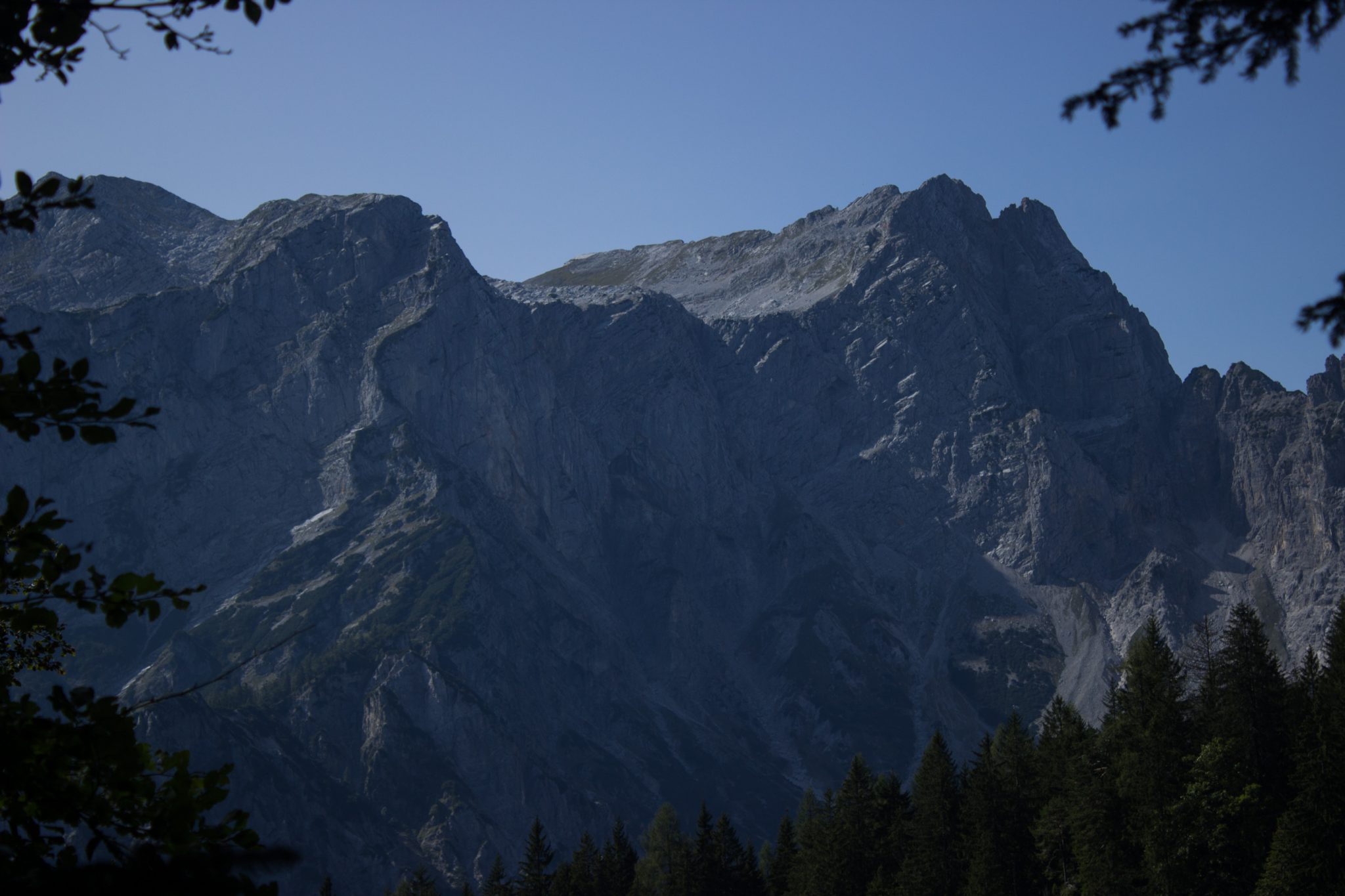 Wandern zur Ennstaler Hütte im Nationalpark Gesäuse im Bundesland Steiermark in Österreich, Wanderweg in den Ennstaler Alpen ab Parkplatz Gstatterboden, Blick auf dichten Wald und die imposanten Berge im Gesäuse, steile Felswände türmen sich auf, warmer Tag im Spätsommer