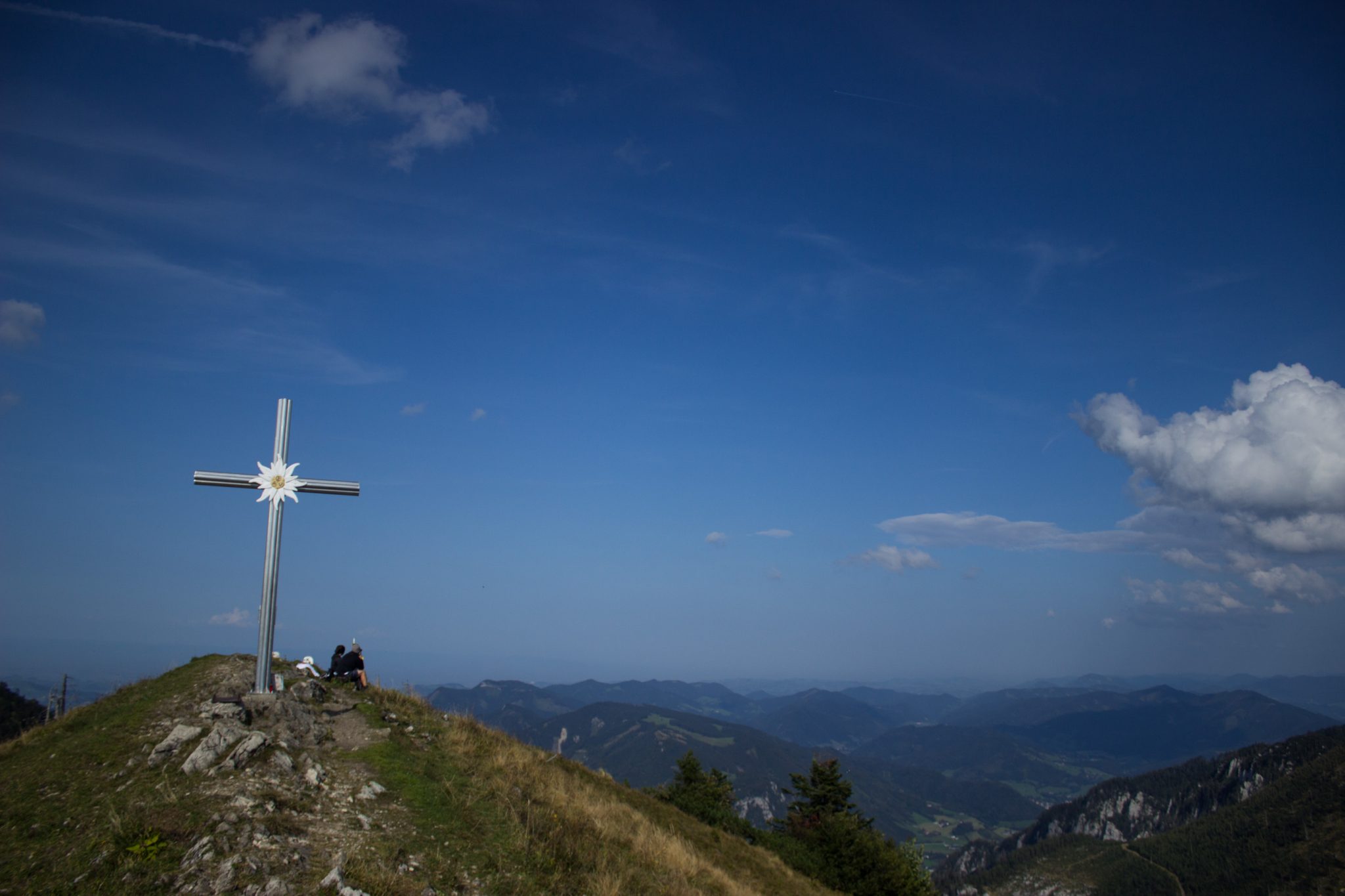 Wanderung zur Ennser Hütte und auf den Almkogel vom Parkplatz Bamacher bei  Großraming in Oberösterreich, Nationalpark-Region Ennstal, beim Almkogel gibt es eine weite und grandiose Aussicht auf die umliegende Bergwelt der Oberösterreichischen Voralpen, Blick auf das Gipfelkreuz des Almkogels, Wanderer genießen die Aussicht