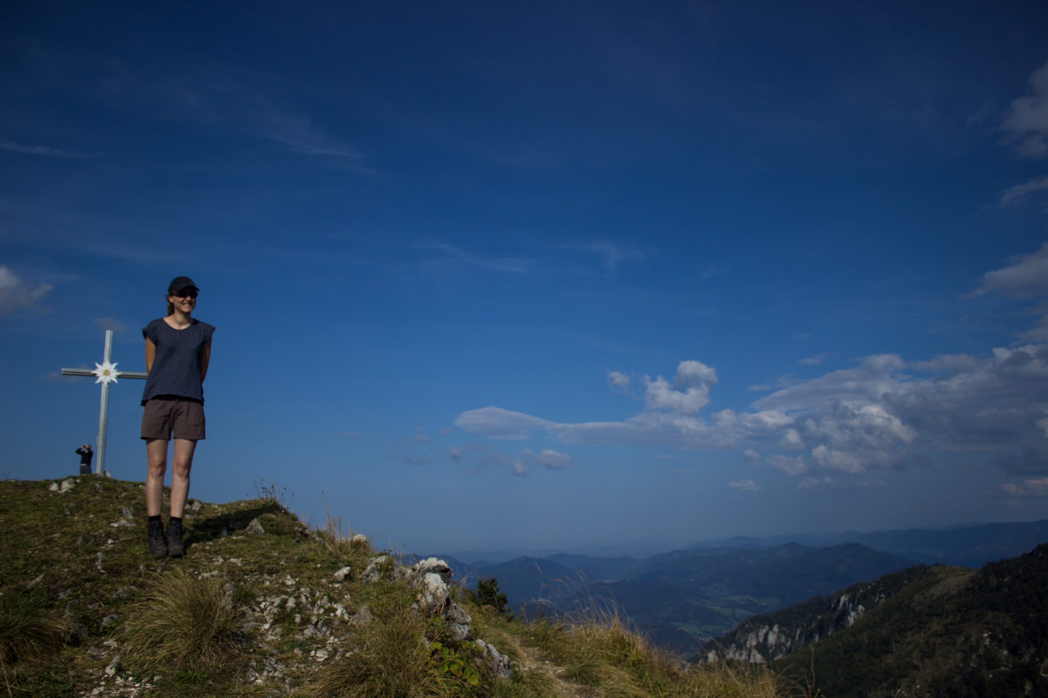 Wanderung zur Ennser Hütte und auf den Almkogel vom Parkplatz Bamacher bei  Großraming in Oberösterreich, Nationalpark-Region Ennstal, beim Almkogel gibt es eine weite und grandiose Aussicht auf die umliegende Bergwelt der Oberösterreichischen Voralpen, Wanderer genießt nach Erreichen des Gipfelkreuzes die Aussicht, herrlicher Wandertag im Sommer