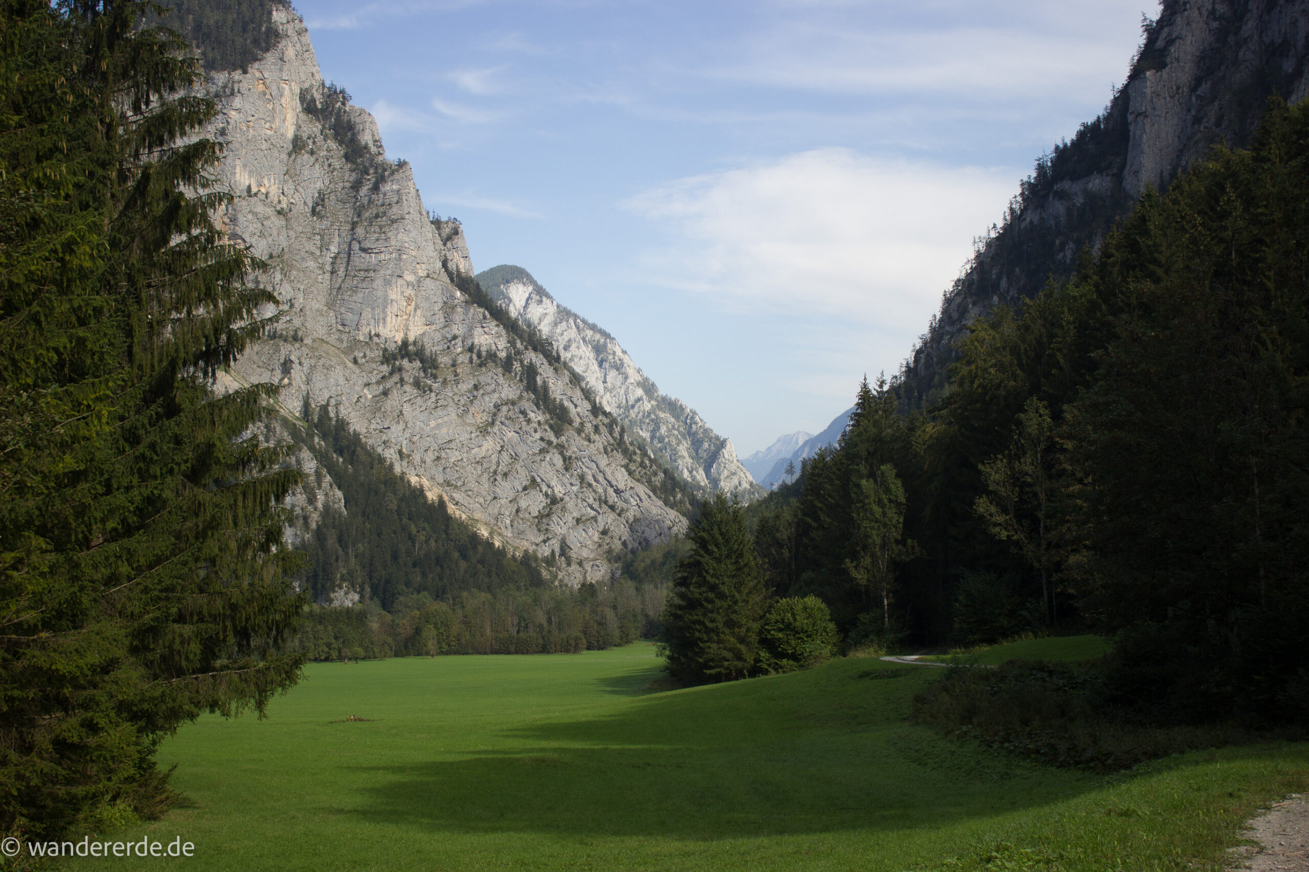 Wandern im Nationalpark Gesäuse - Rundweg mit Goferhütte im Bundesland Steiermark in Österreich, Wanderweg in den Ennstaler Alpen, nach Erreichen der Vordergoferalm geht es in Serpentinen runter ins Tal im Nationalpark Gesäuse, Wanderer auf Forststraße im Tal umgeben von Wald, saftig grünen Wiesen und steil aufragenden Bergen