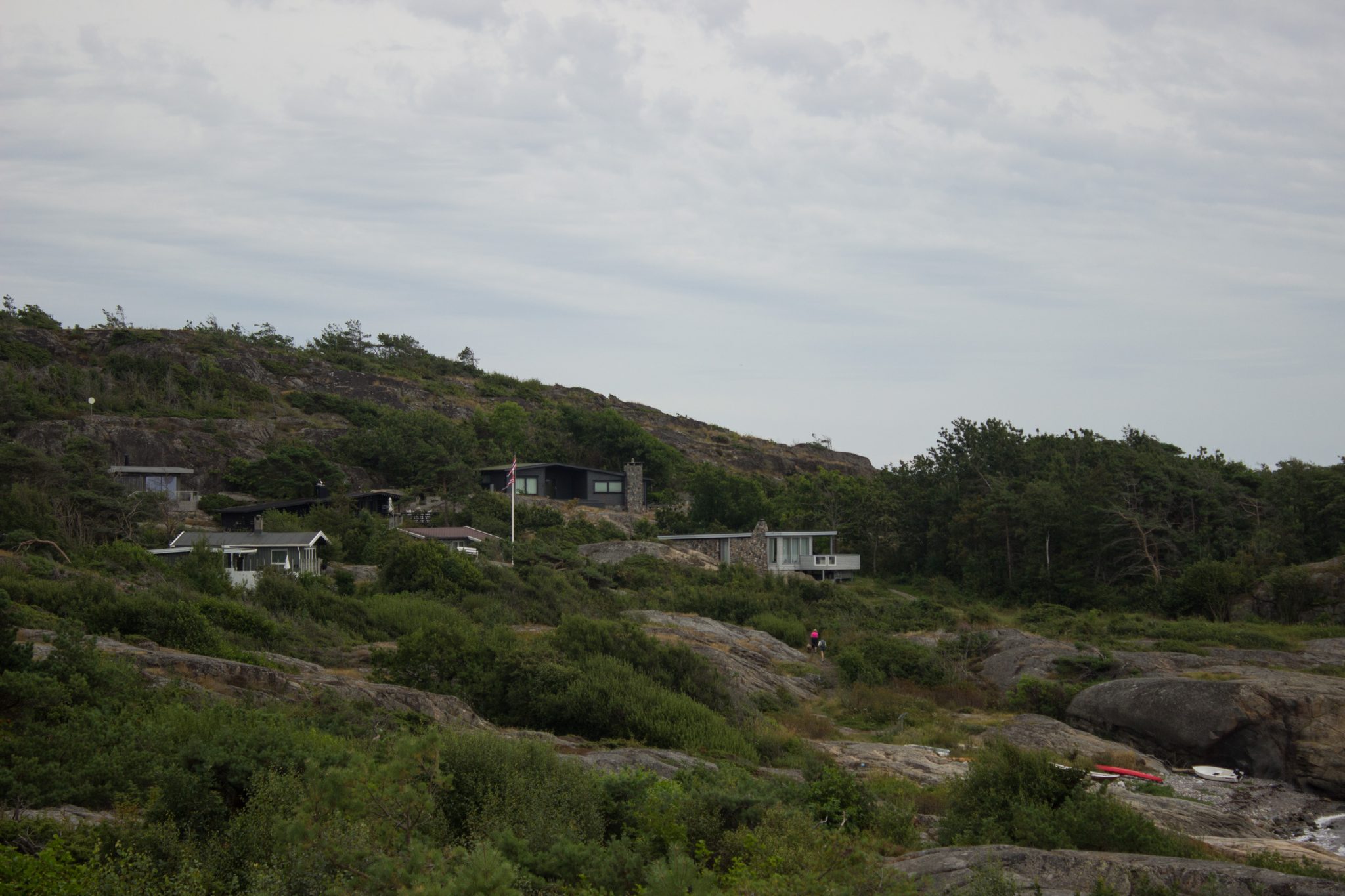 Küstenwanderung von Stavern nach Nevlunghavn, auf dem Kyststien entlang der Schärenküste von Vestfold in Südnorwegen, Wanderung entlang des Küstenpfads, Blick auf Häuser entlang des Pfades über große Felsen, Küstenvegetation und Blick auf Wald