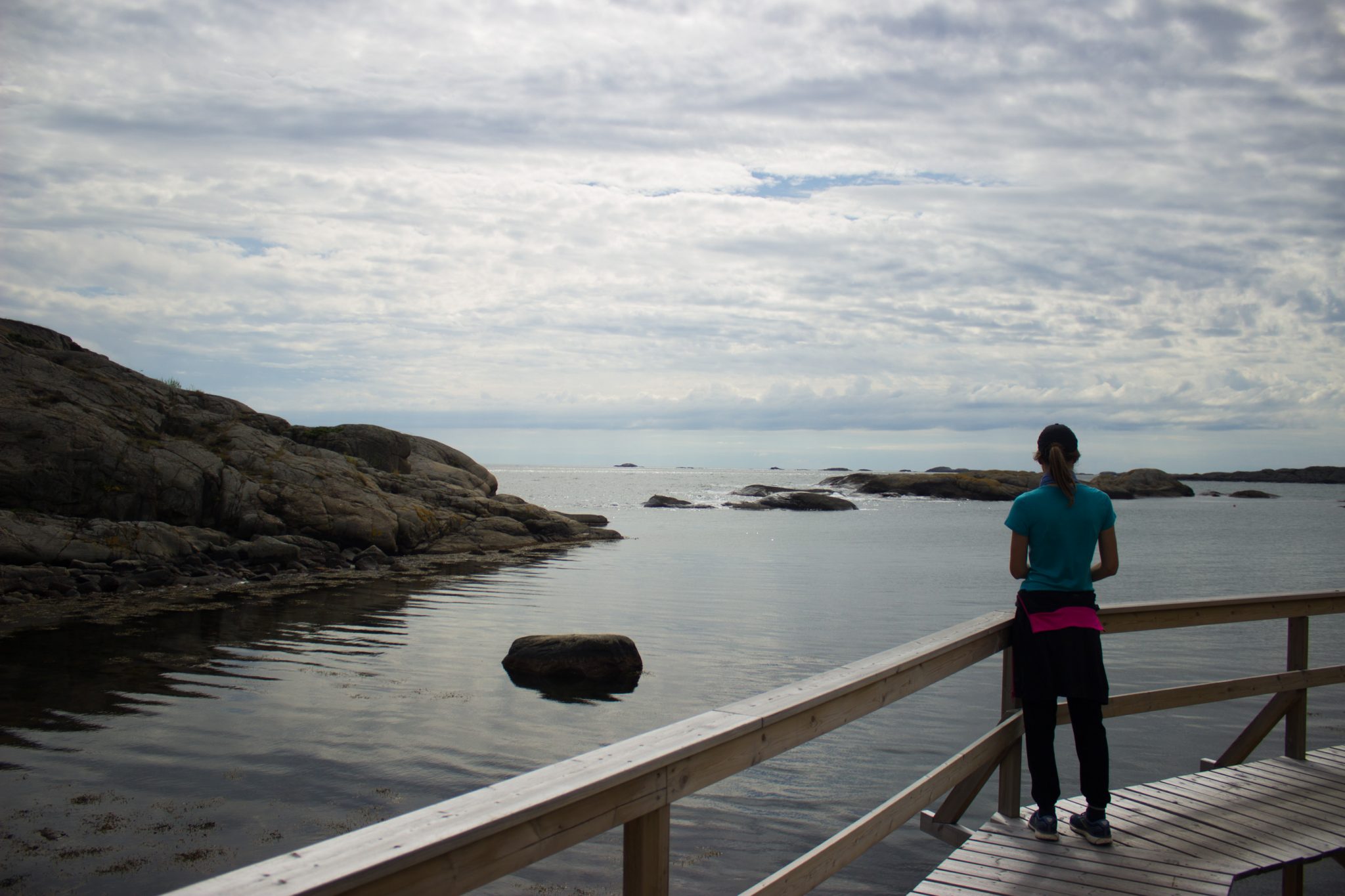 Küstenwanderung von Stavern nach Nevlunghavn, auf dem Kyststien entlang der Schärenküste von Vestfold in Südnorwegen, Wanderer genießt Aussicht auf das weite Meer, Wanderweg verläuft über Holzbalken am Fels entlang
