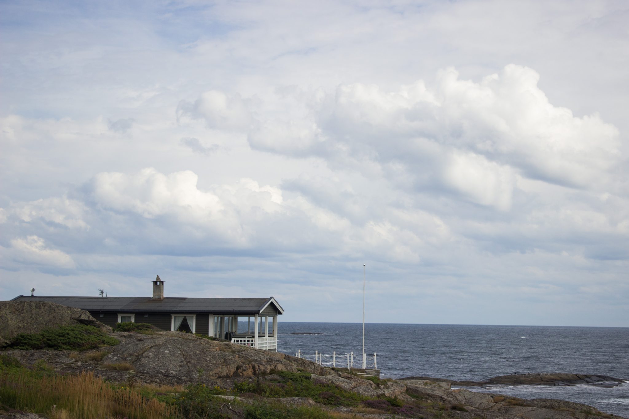 Küstenwanderung von Stavern nach Nevlunghavn, auf dem Kyststien entlang der Schärenküste von Vestfold in Südnorwegen, Wanderung entlang des Küstenpfads, Wanderweg am Meer entlang über große Felsen, Haus direkt an der Küste