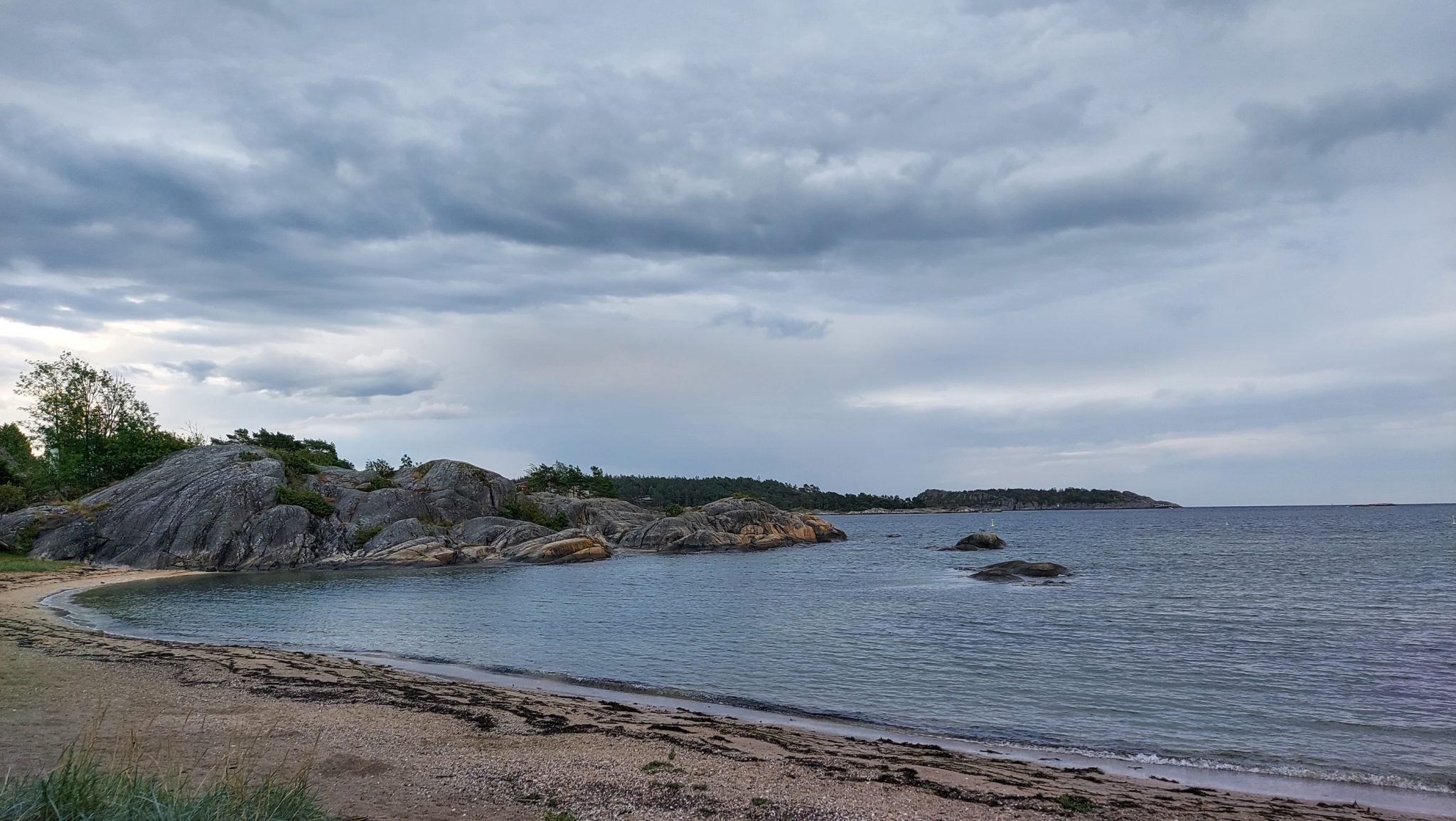 Küstenwanderung von Stavern nach Nevlunghavn, auf dem Kyststien entlang der Schärenküste von Vestfold in Südnorwegen, Wanderung entlang des Küstenpfads, kleine Bucht mit Felsen und Sandstrand entlang des Wanderweges, Aussicht auf das Meer