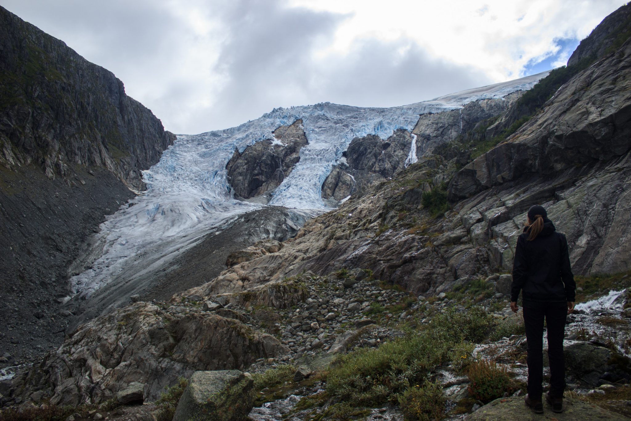 Wandern zum Buarbreen im Folgefonna Nationalpark, Wanderung in der Nähe von Odda mit Aussicht auf den Gletscher Buarbreen und Wasserfälle, Wanderer blickt auf den Gletscher und die umliegenden Berge während der Wanderung zum Buarbreen