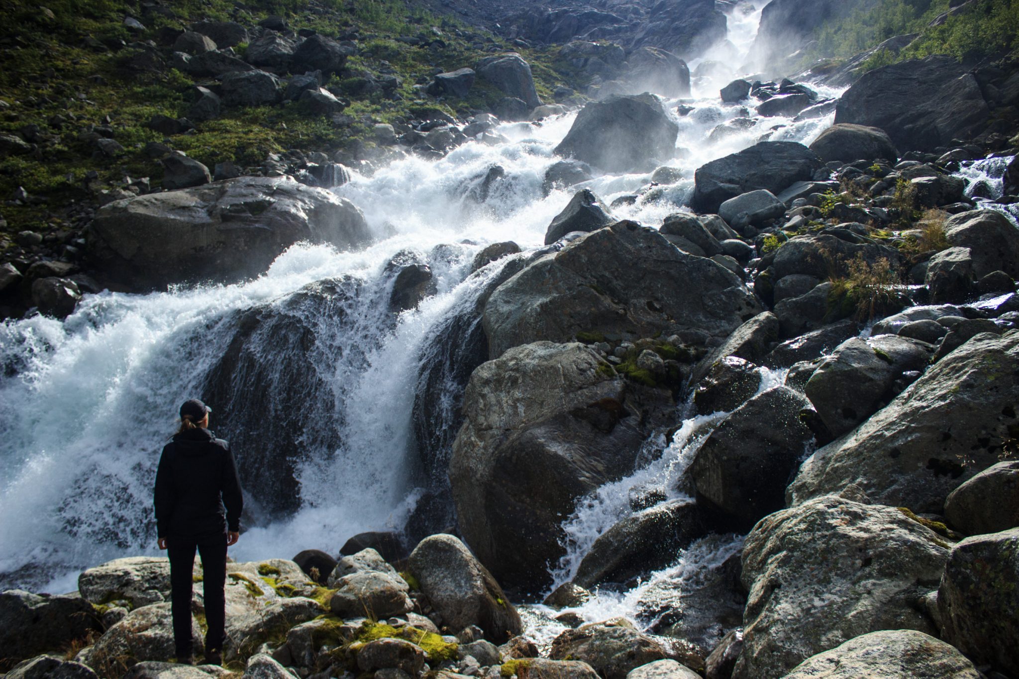 Wandern zum Buarbreen im Folgefonna Nationalpark, Wanderung in der Nähe von Odda mit Aussicht auf den Gletscher Buarbreen und Wasserfälle, Wanderer genießt Blick auf den reißenden Fluss und die umliegenden riesigen Felsen