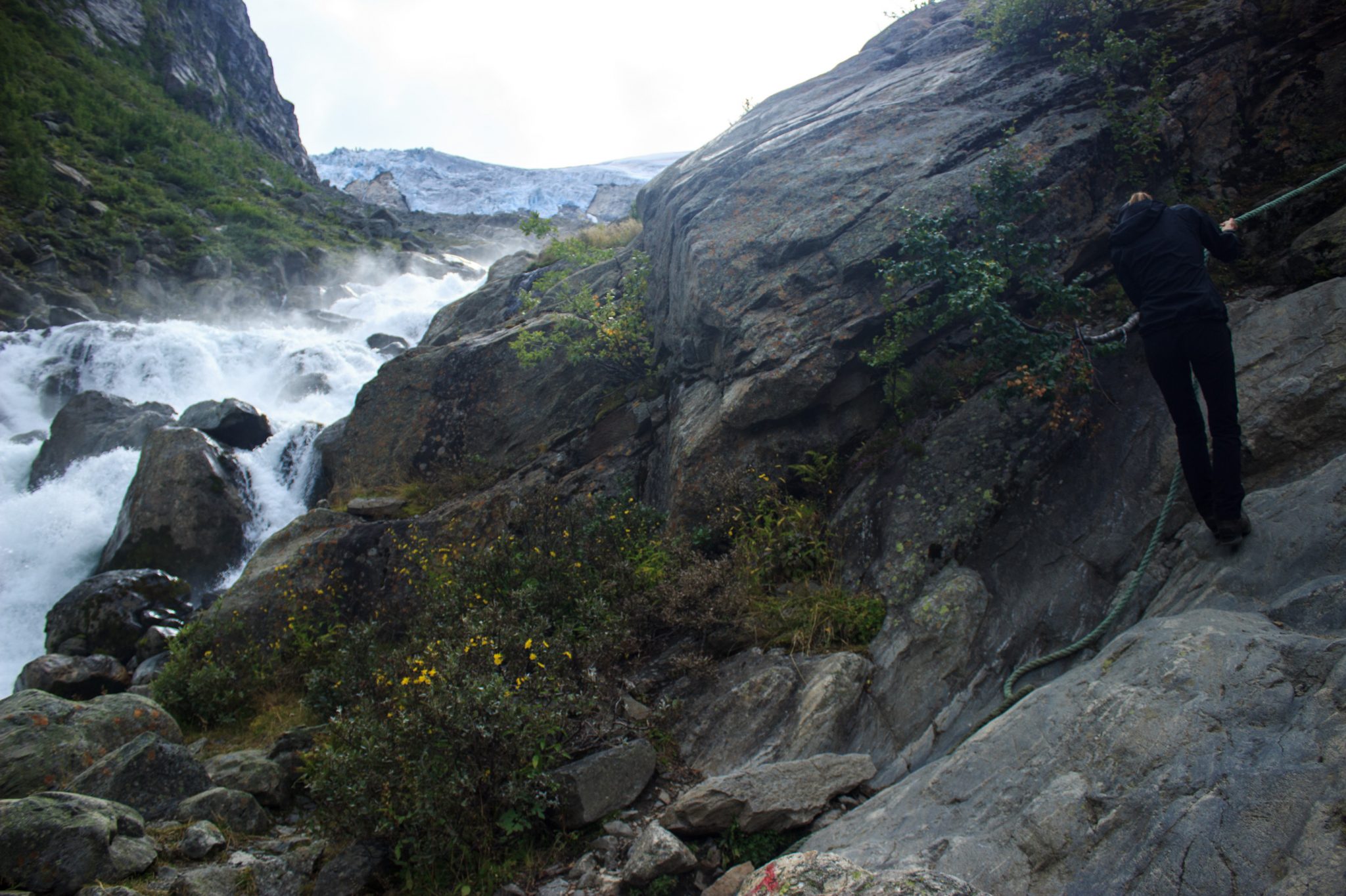 Wandern zum Buarbreen im Folgefonna Nationalpark, Wanderung in der Nähe von Odda mit Aussicht auf den Gletscher Buarbreen und Wasserfälle, Wanderer unterwegs auf teils steilem Wanderweg, teilweise gesichert mit Seilen, Fluss und Gletscher im Hintergrund zu sehen