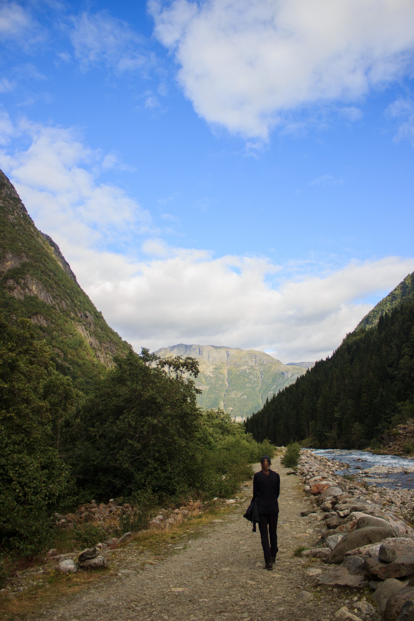 Wandern zum Buarbreen im Folgefonna Nationalpark, Wanderung in der Nähe von Odda mit Aussicht auf den Gletscher Buarbreen und Wasserfälle, Wanderer unterwegs auf Wanderweg unten im Tal entlang des Flusses, Blick auf die gegenüberliegenden Berge vom Gletscher Buarbreen