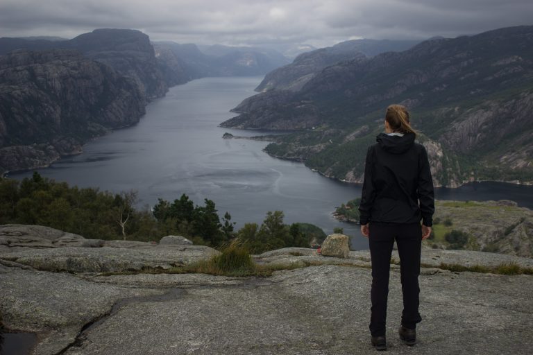 Wanderung beim Lysefjord mit Blick auf den Preikestolen, Startpunkt der Wanderung auf den Sokkaknuten ist beim Lysefjord Hyttegrend, Aussicht auf den Pulpit Rock, Wanderer genießt Aussicht auf den Lysefjord und den Preikestolen