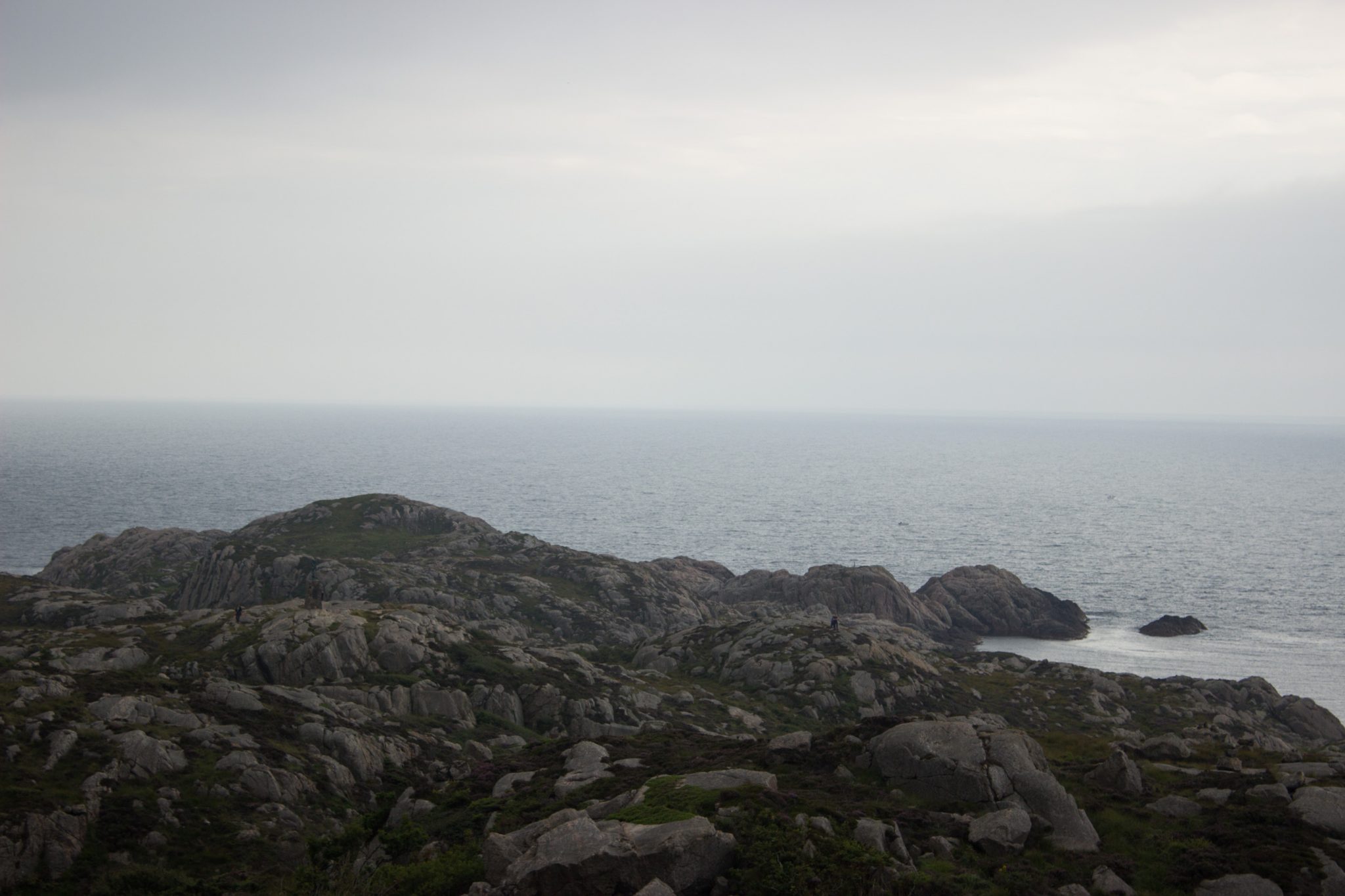 Wanderungen beim Kap Lindesnes, südlichster Punkt Norwegens, am Südkap in Norwegen, Wanderweg führt über große Felsen, grüne Vegetation an der Küste, Aussicht auf das weite Meer
