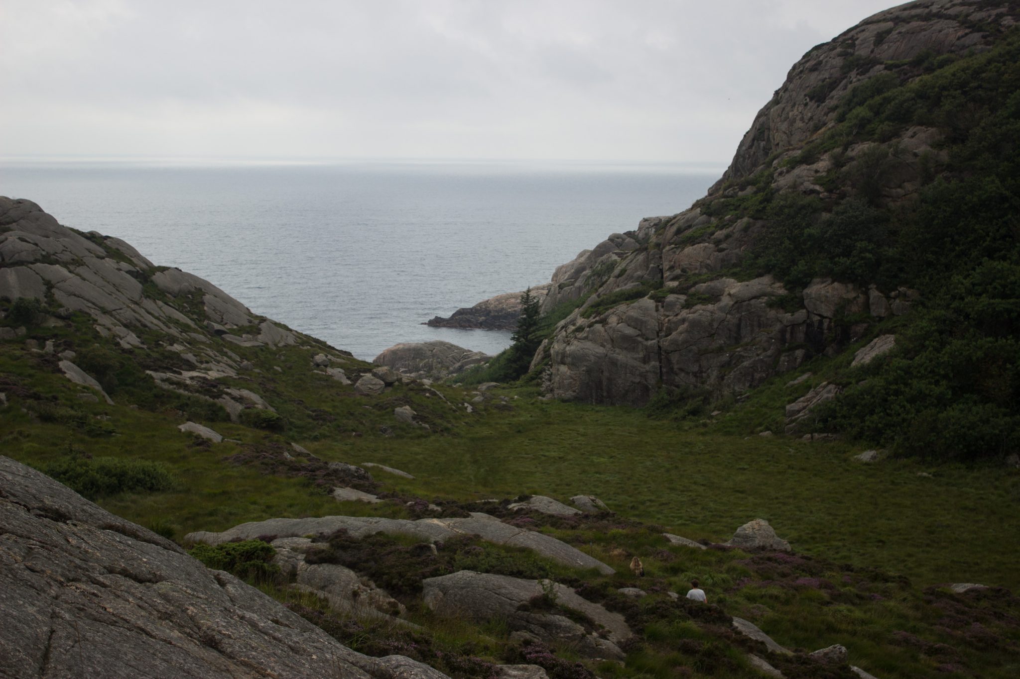 Wanderungen beim Kap Lindesnes, südlichster Punkt Norwegens, am Südkap in Norwegen, Wanderer unterwegs auf schmalem Pfad entlang großer Felsen, grüne Vegetation an der Küste, Heidelandschaft, Aussicht auf das weite Meer