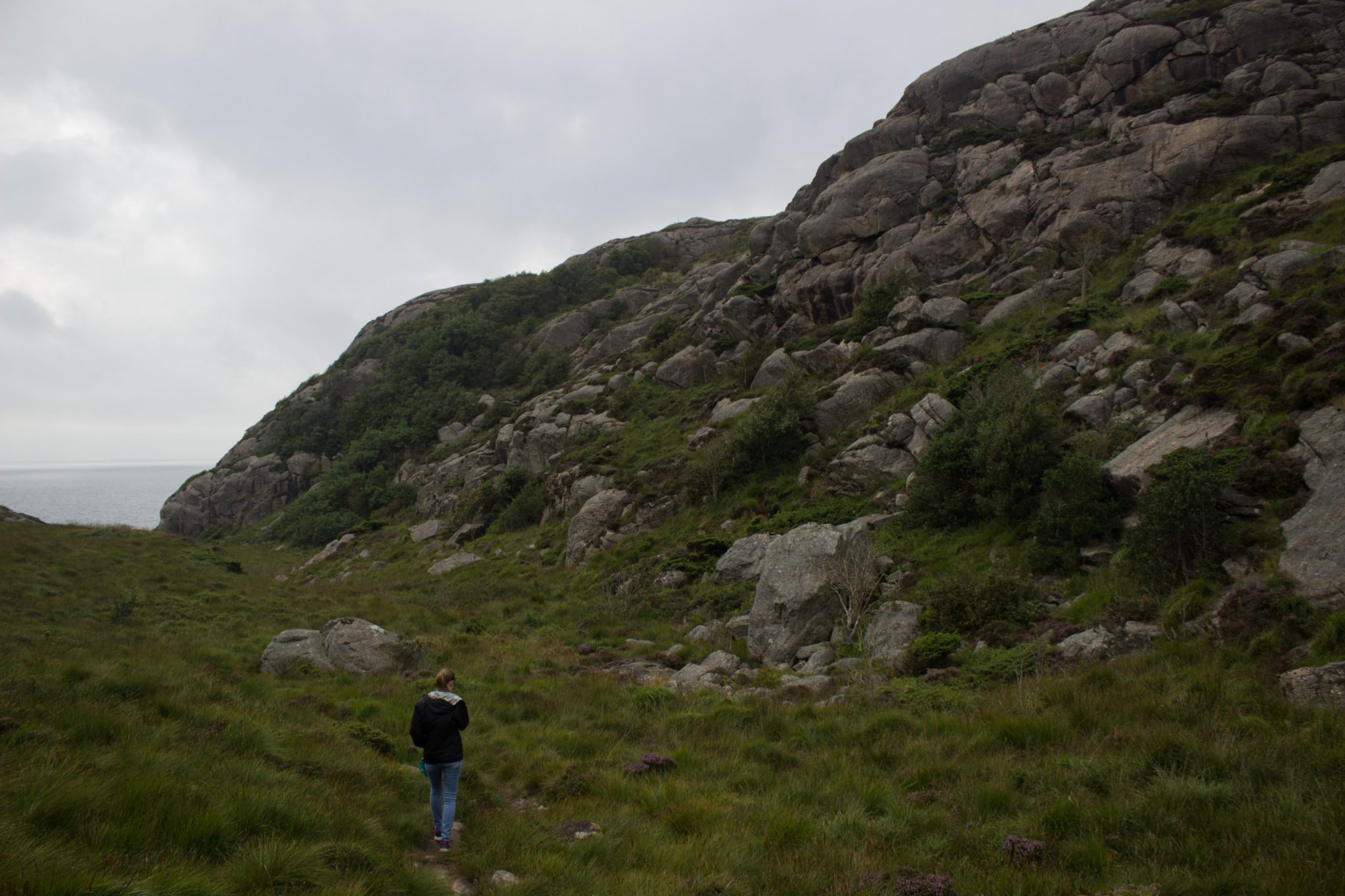 Wanderungen beim Kap Lindesnes, südlichster Punkt Norwegens, am Südkap in Norwegen, Wanderer unterwegs auf schmalem Pfad entlang großer Felsen, grüne Vegetation an der Küste, Heidelandschaft, Aussicht auf das weite Meer
