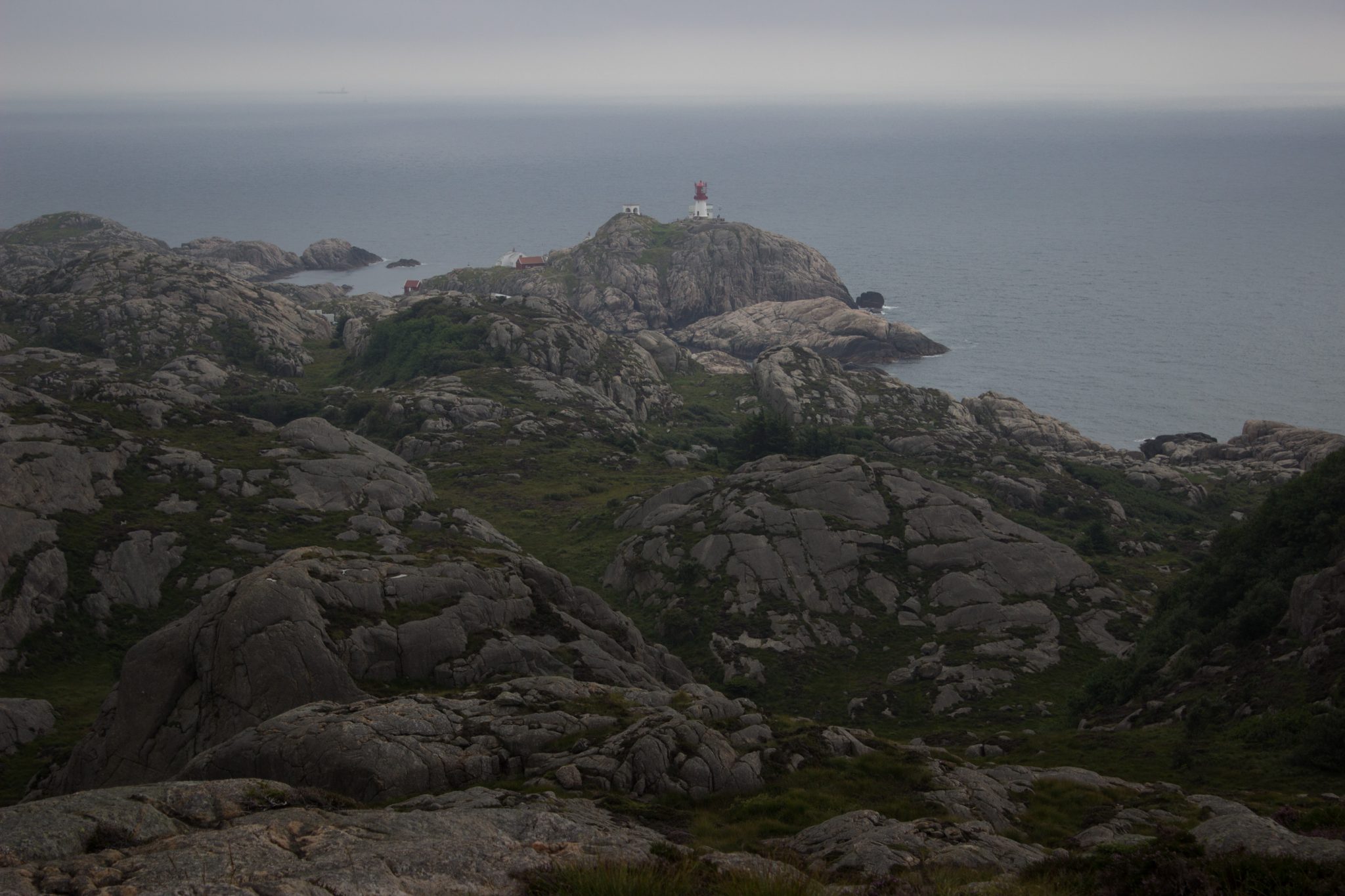 Wanderungen beim Kap Lindesnes, südlichster Punkt Norwegens, am Südkap in Norwegen, Wanderer unterwegs auf schmalem Pfad entlang großer Felsen, grüne Vegetation an der Küste, Heidelandschaft, Aussicht auf das weite Meer und den Leuchtturm Lindesnes Fyr