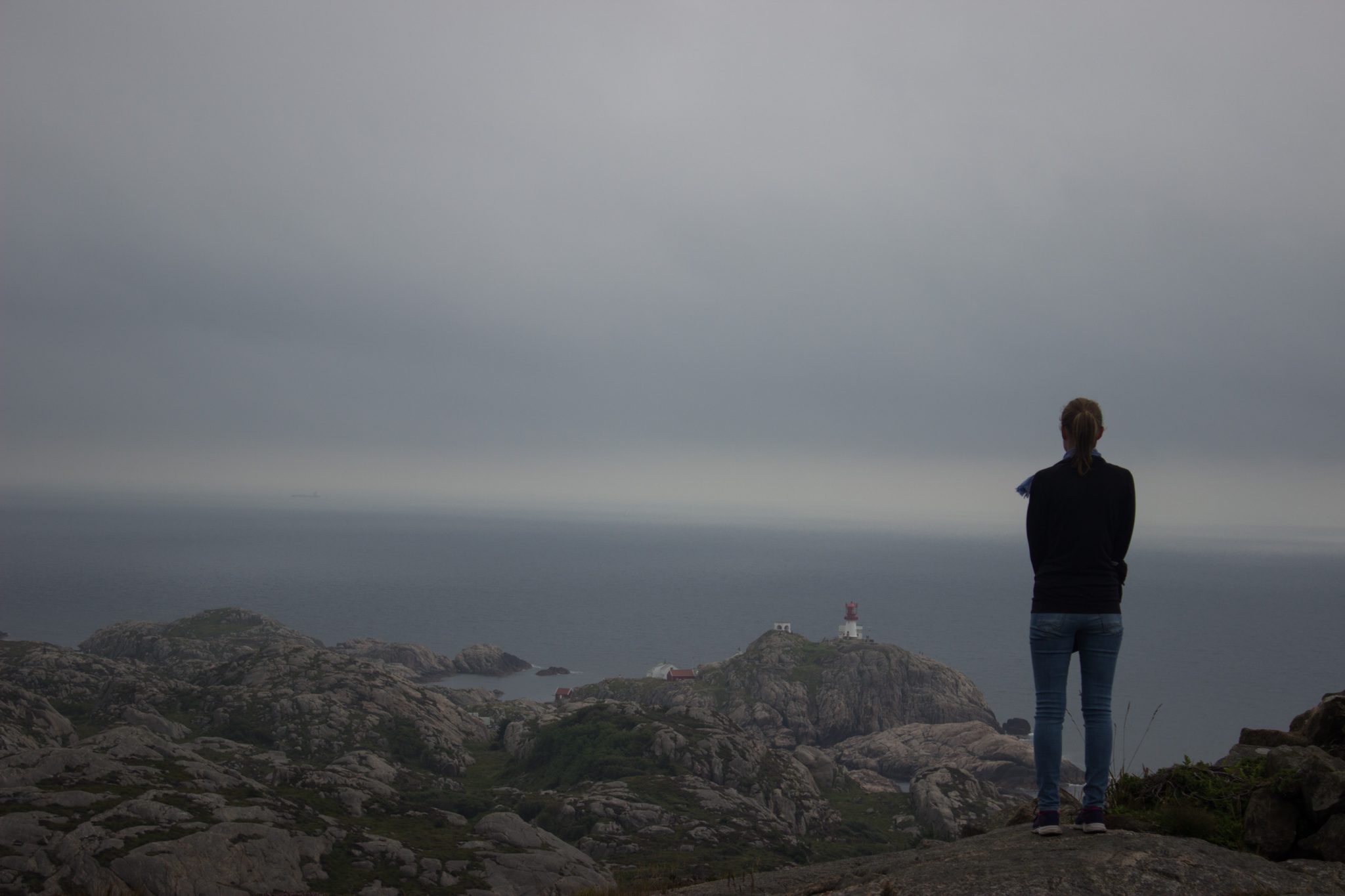 Wanderungen beim Kap Lindesnes, südlichster Punkt Norwegens, am Südkap in Norwegen, Wanderer unterwegs auf schmalem Pfad entlang großer Felsen, grüne Vegetation an der Küste, Heidelandschaft, Aussicht auf das weite Meer und den Leuchtturm Lindesnes Fyr