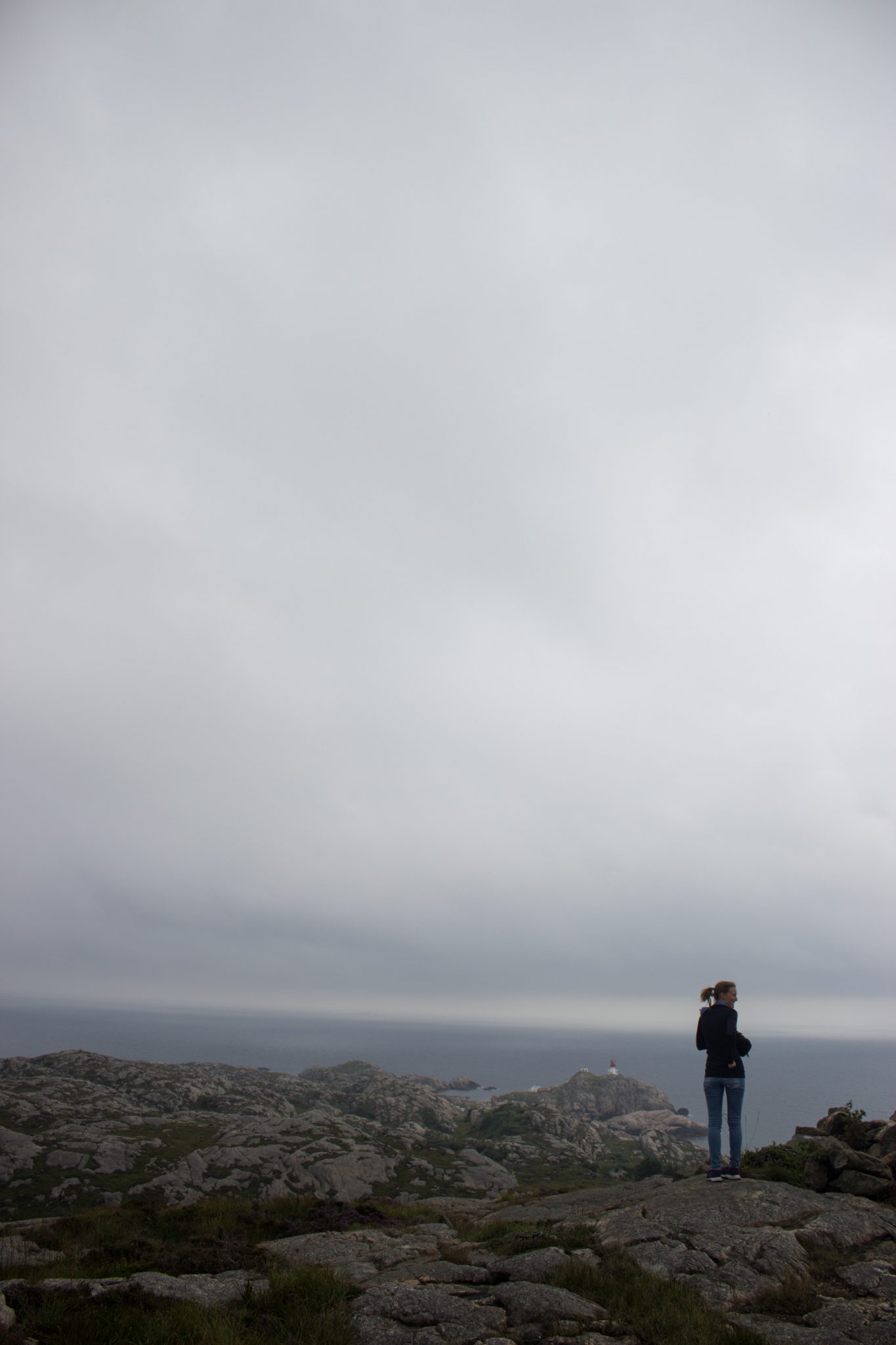 Wanderungen beim Kap Lindesnes, südlichster Punkt Norwegens, am Südkap in Norwegen, Wanderer unterwegs auf schmalem Pfad entlang großer Felsen, Aussicht auf das weite Meer und den Leuchtturm Lindesnes Fyr