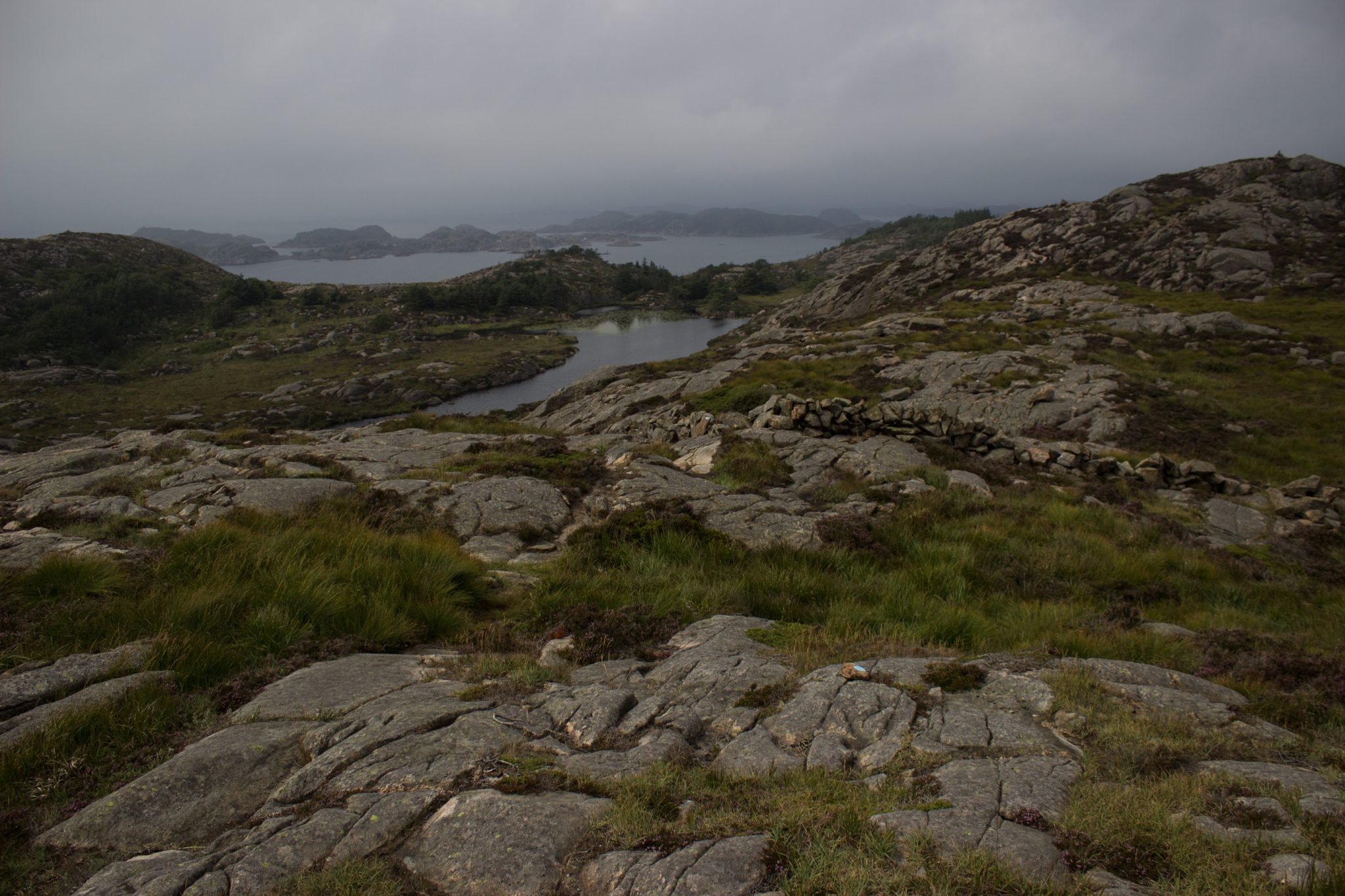 Wanderungen beim Kap Lindesnes, südlichster Punkt Norwegens, am Südkap in Norwegen, Wanderer unterwegs auf schmalem Pfad entlang großer Felsen, grüne Vegetation an der Küste, Heidelandschaft, Aussicht auf das weite Meer